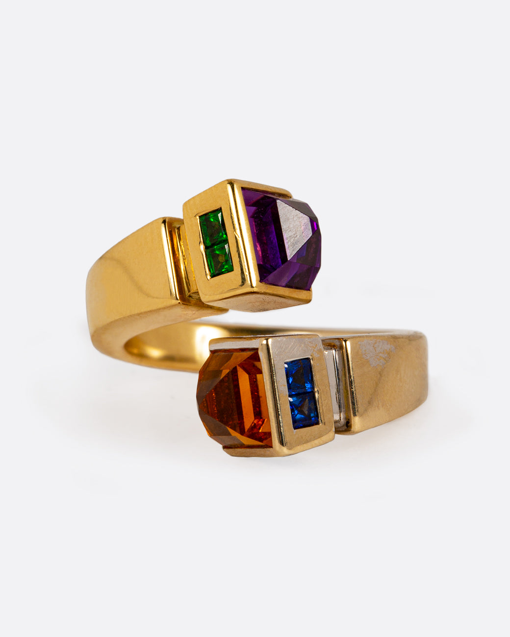 A meld of yellow and white gold, this open wrap ring is tipped with citrine, amethyst, sapphires, and emeralds. The band narrows at the back. Shown from the front.