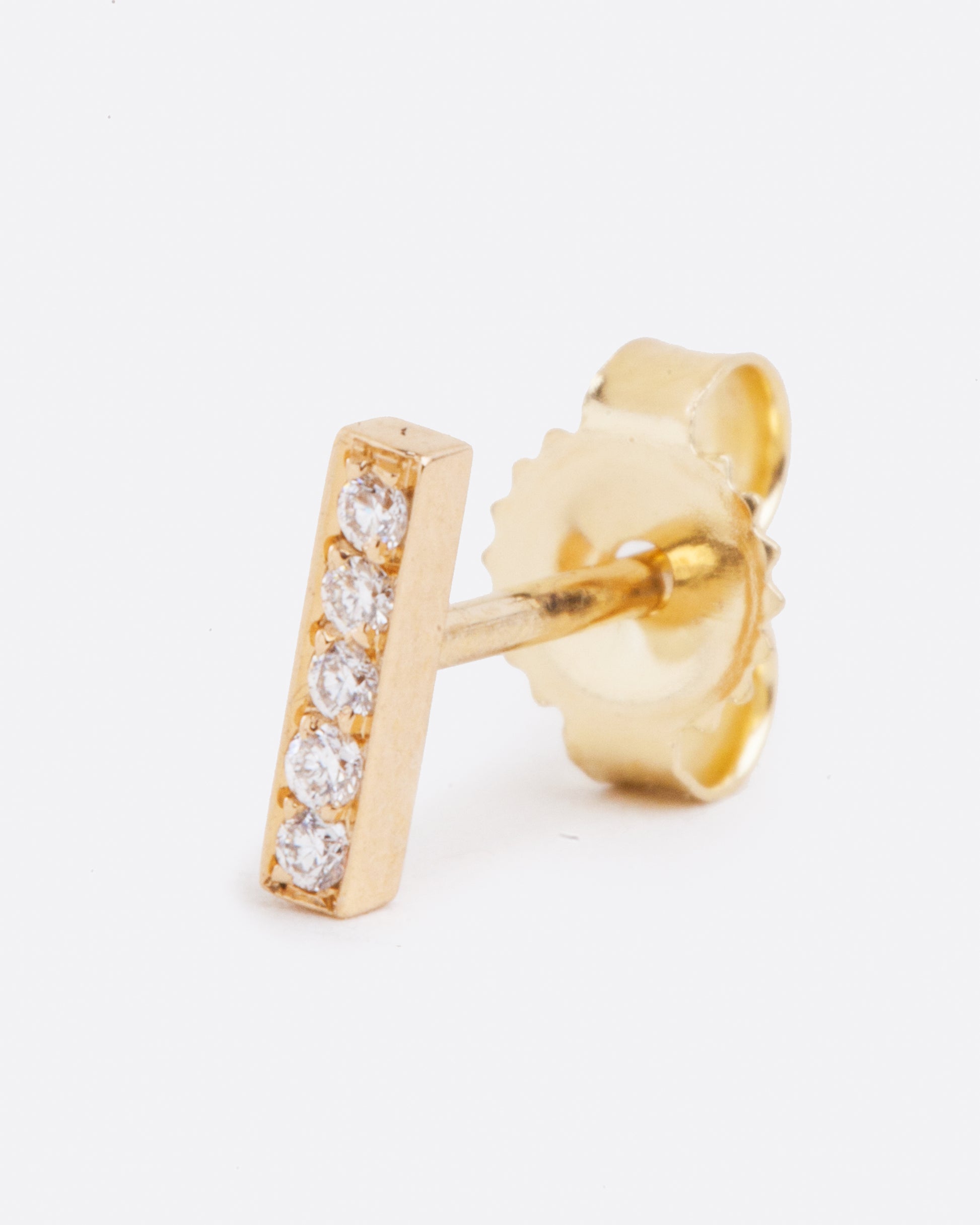 A yellow gold bar stud earring with five white diamonds. Shown standing up from the front.