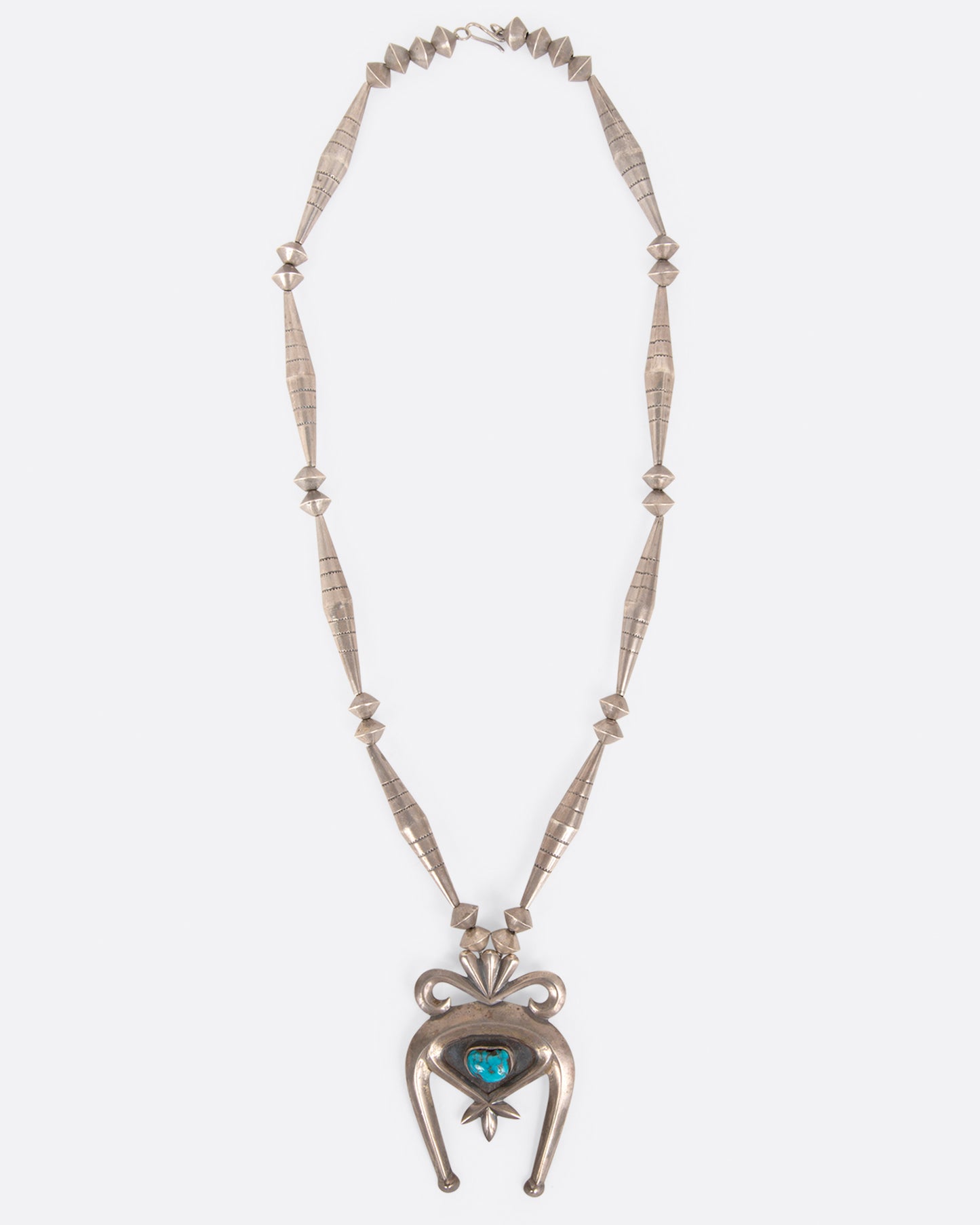 A vintage silver naja necklace with a turquoise stone at the center of the pendant, shown from the front.