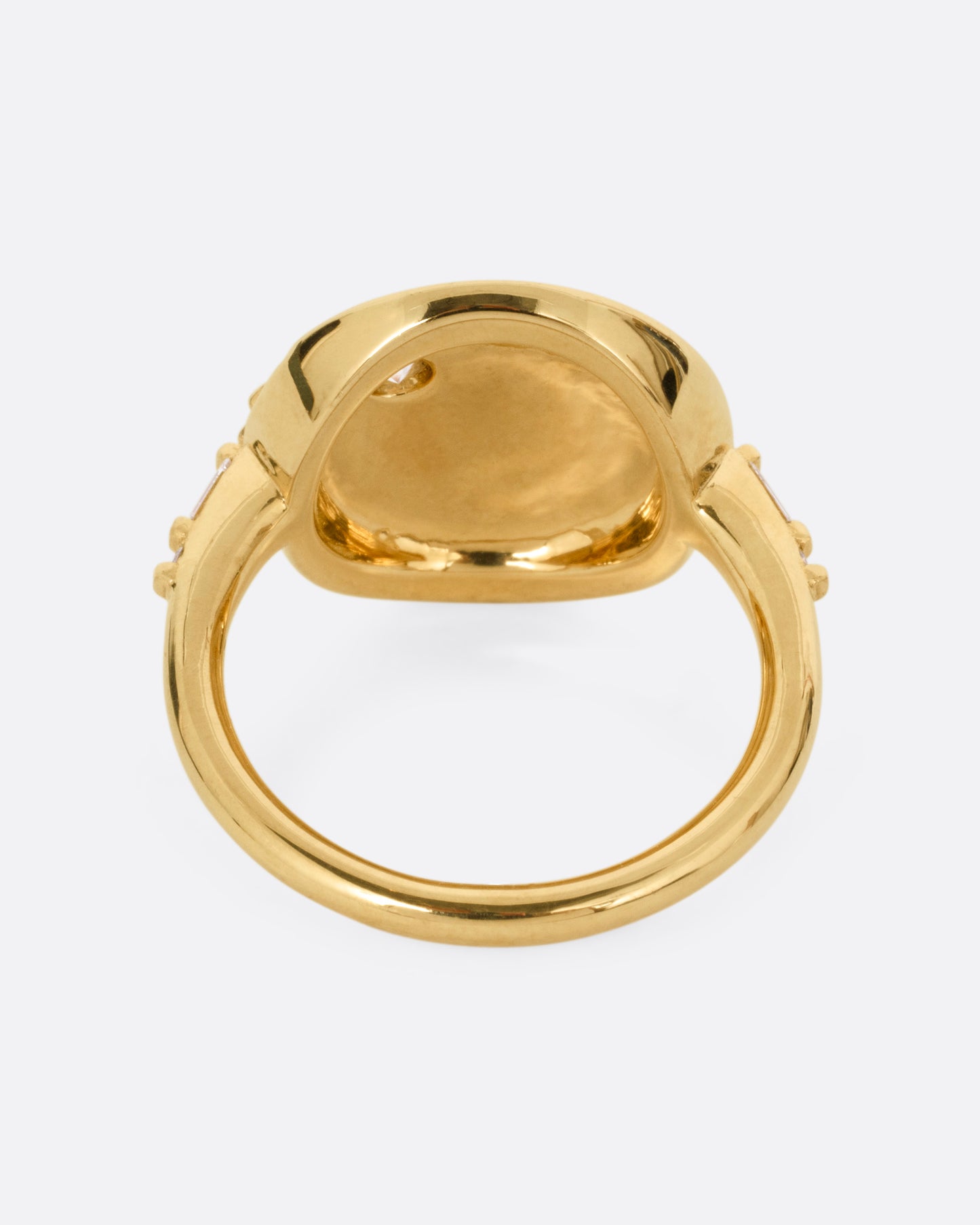 A yellow gold ring with a round face featuring a balance of brilliant round and baguette diamonds. Shown from the back.