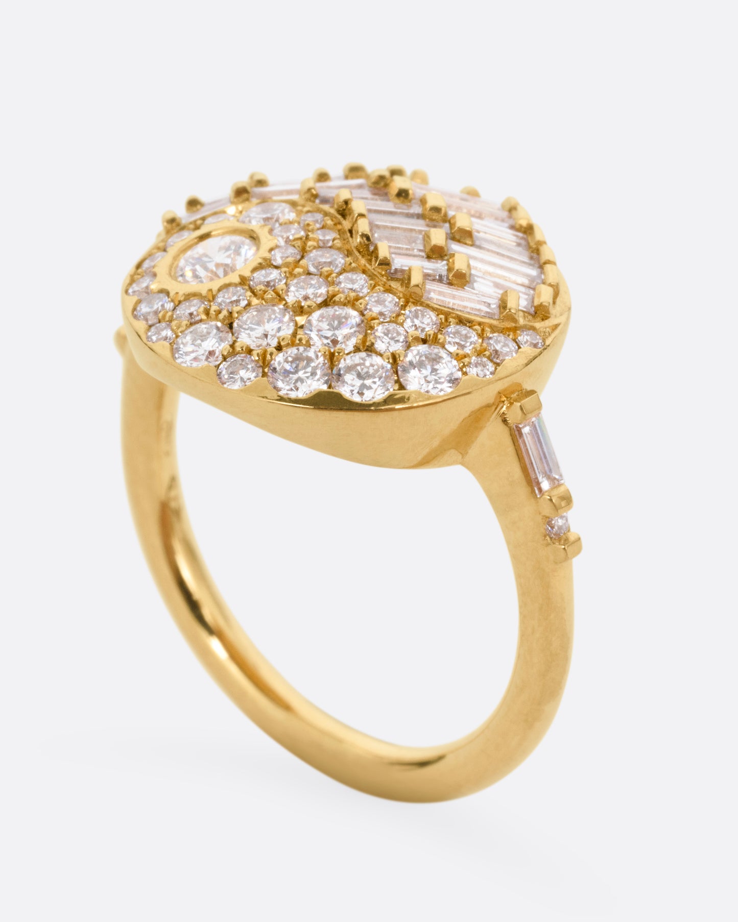 A yellow gold ring with a round face featuring a balance of brilliant round and baguette diamonds. Shown from the side standing up.