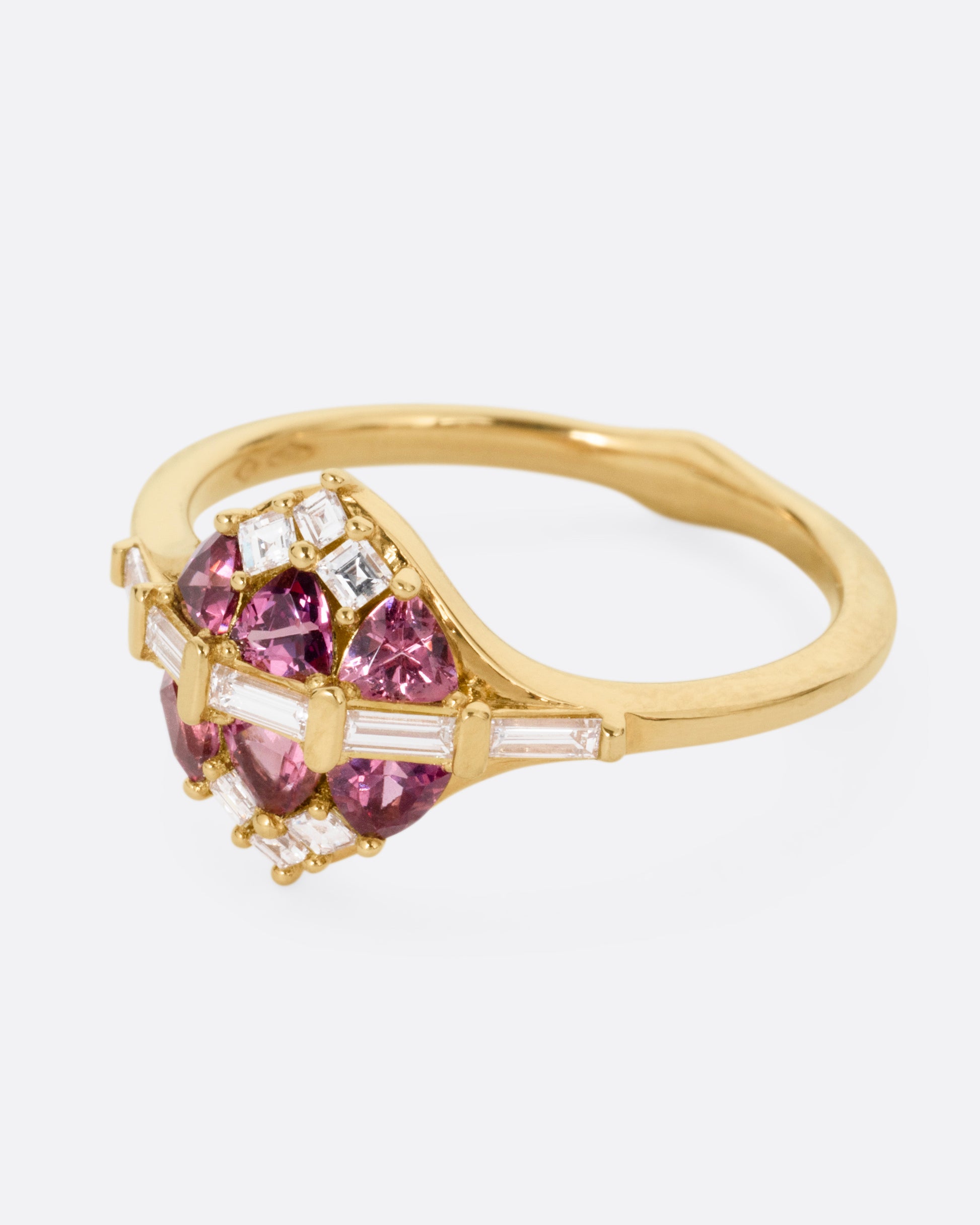 A yellow gold ring with a row of baguette diamonds passing through a cluster of trillion cut garnets and diamond accents. Shown from the side.