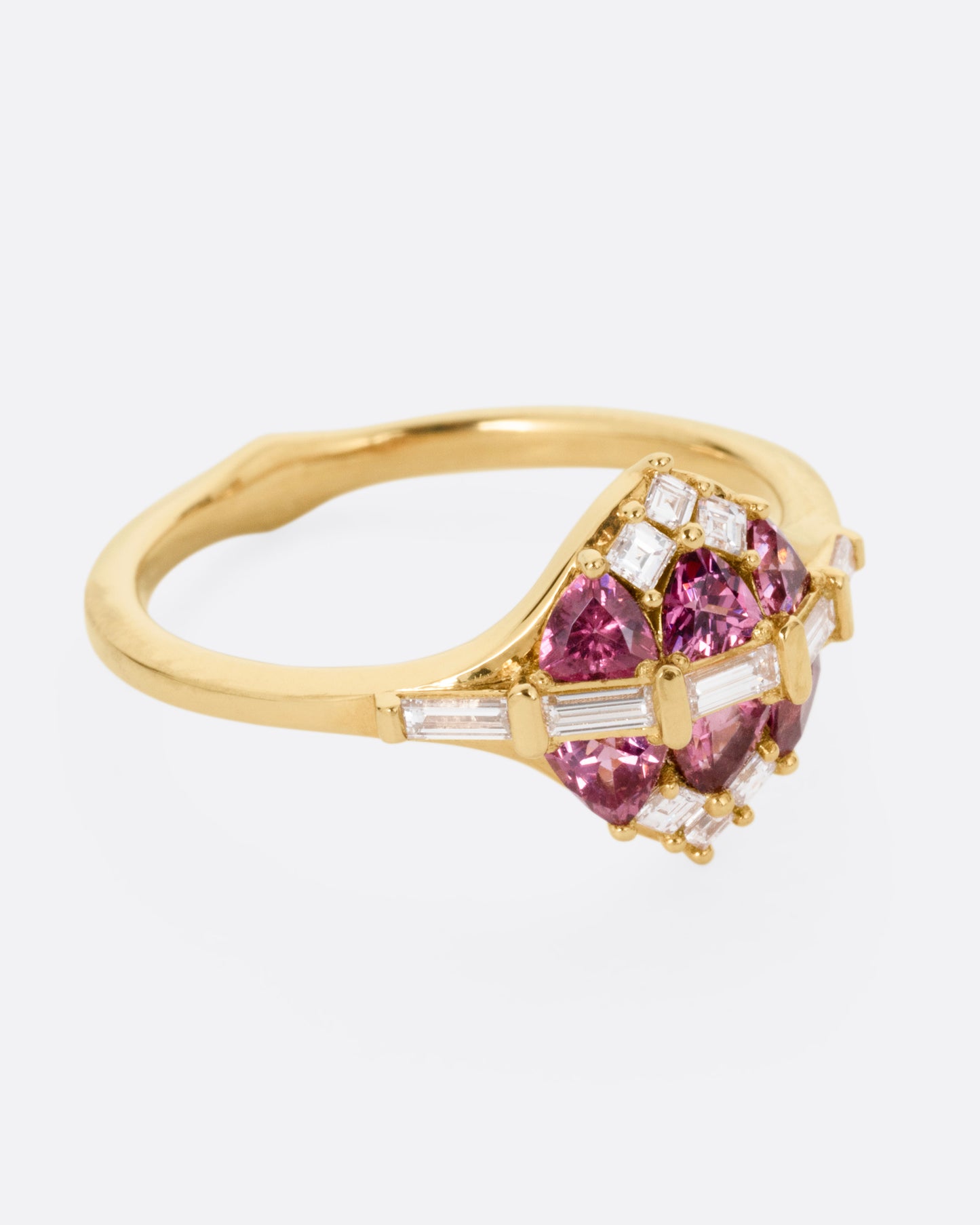 A yellow gold ring with a row of baguette diamonds passing through a cluster of trillion cut garnets and diamond accents. Shown from the side.