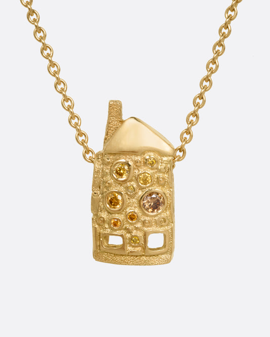 A yellow gold house-shaped pendant with multi-colored diamonds, on a cable chain, shown from the front. 