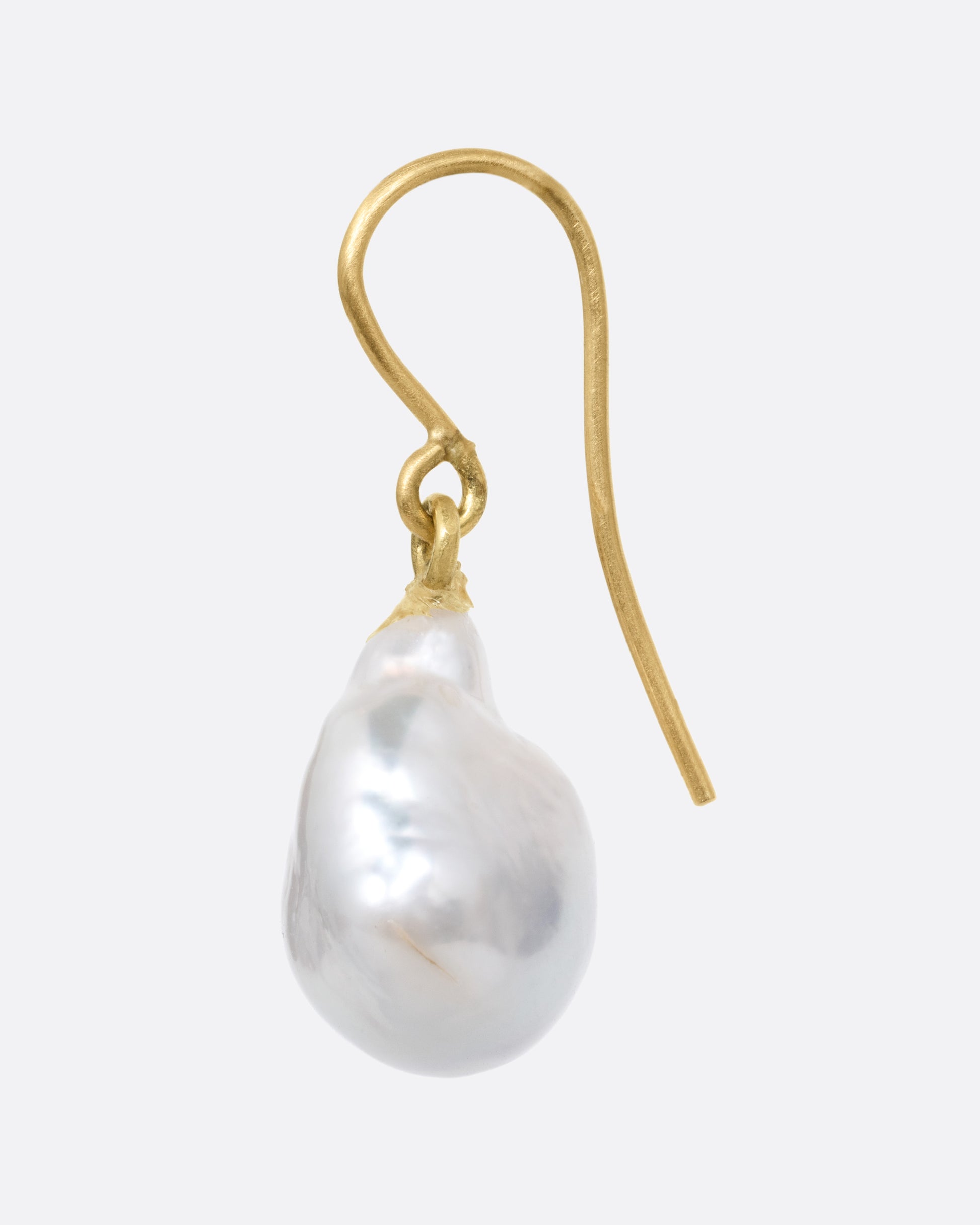 A pearl earring with a yellow gold ear hook, shown from the side.