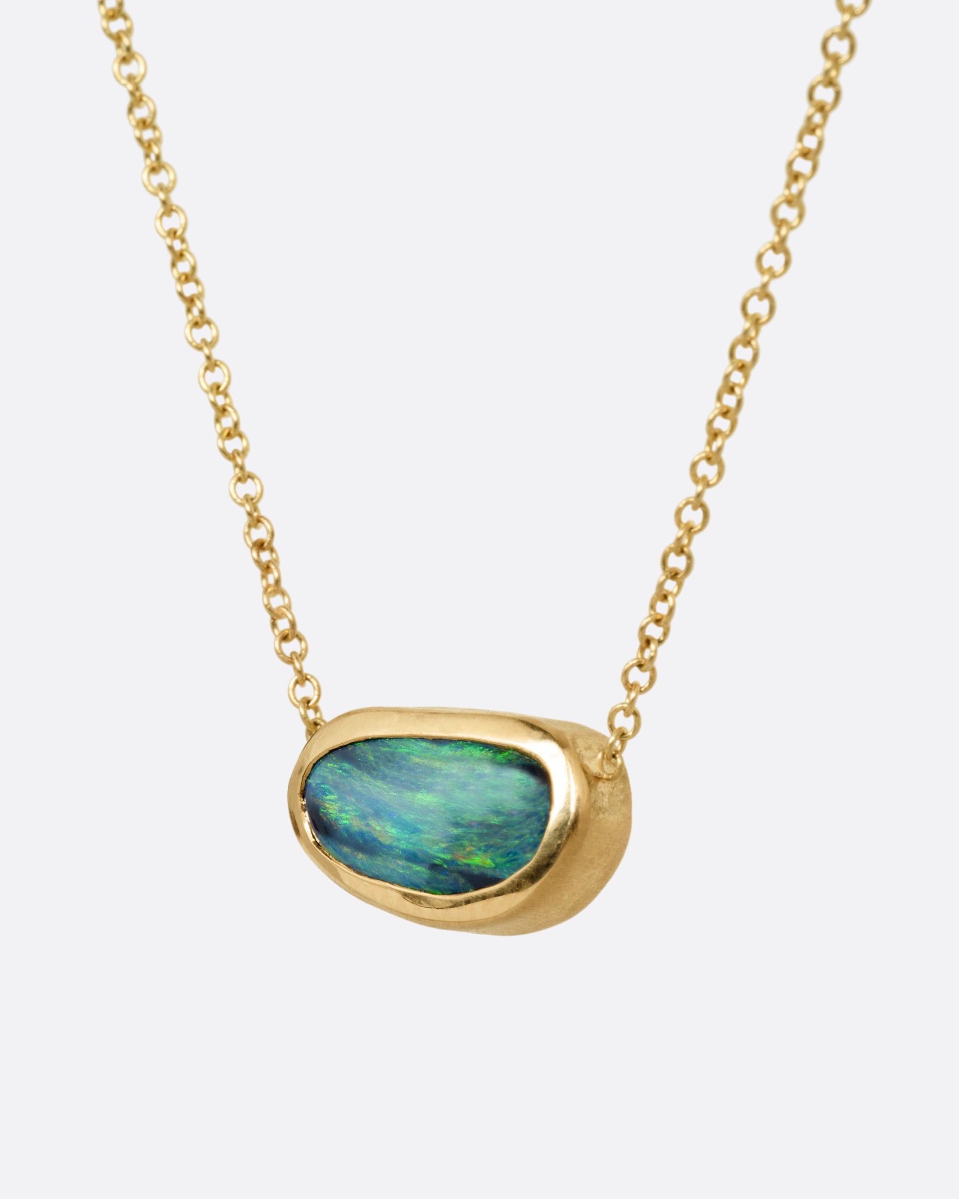 A yellow gold cable chain necklace with a blue-green Australian opal Shown from the side.