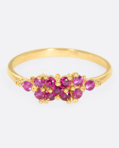 A yellow gold ring with a cluster of rubies arranged on the face. Shown from the front.