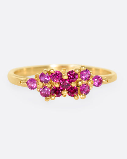 A yellow gold ring with a cluster of rubies arranged on the face. Shown from the front.