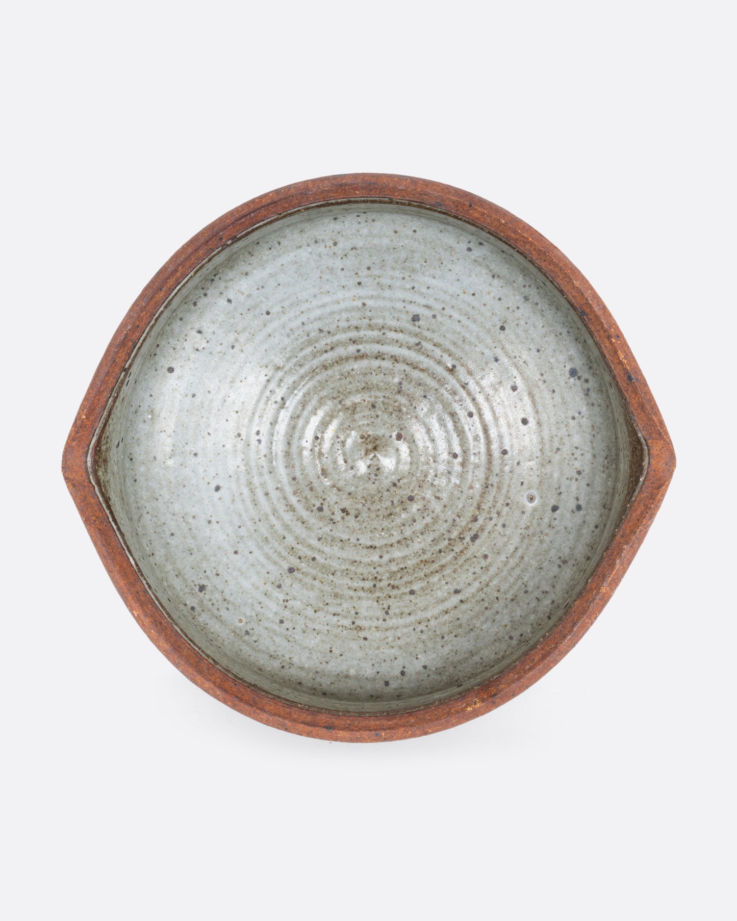 A striped ceramic serving bowl with two spouts. Shown from above.