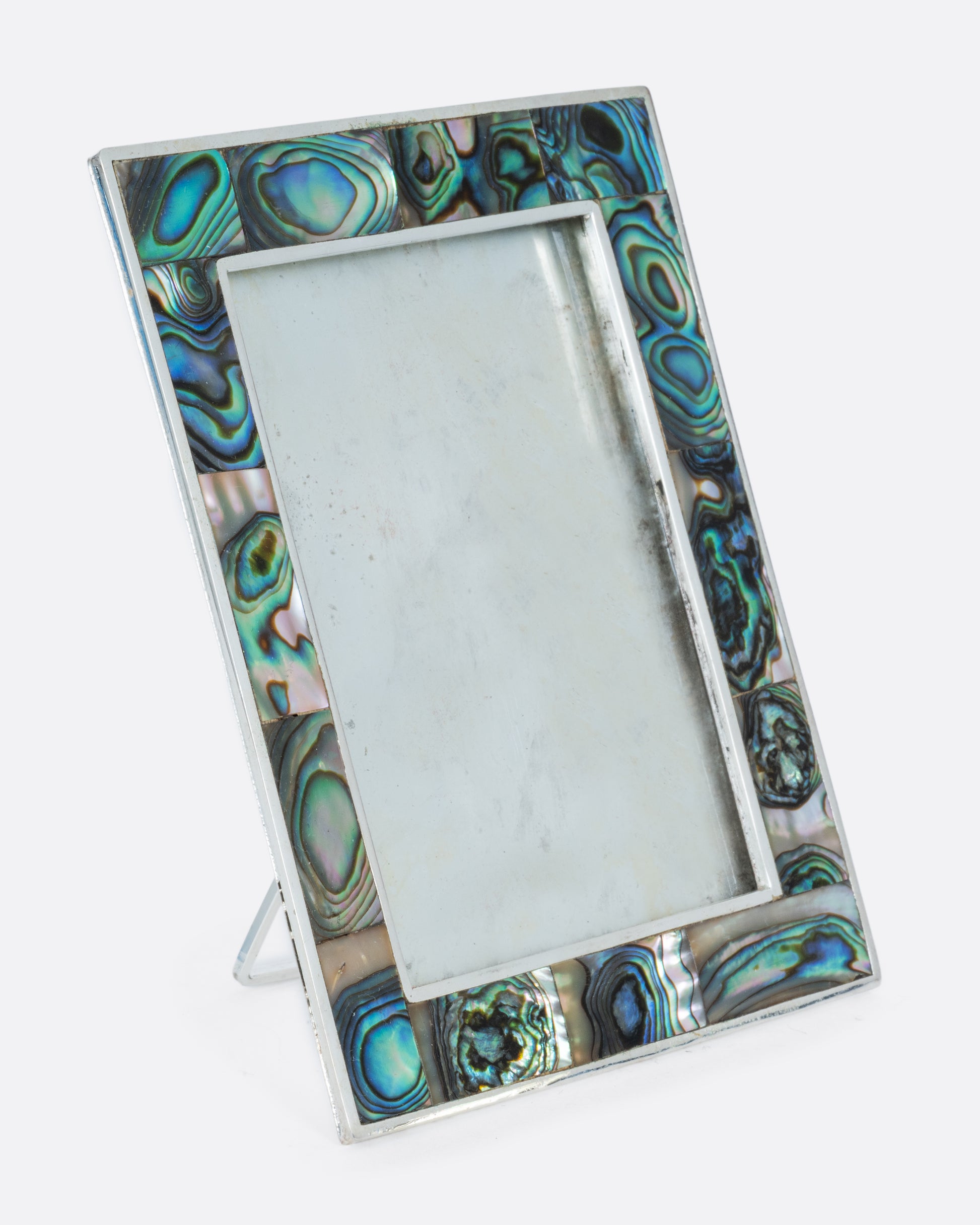 A silver rectangular picture frame with abalone inlay. Shown standing up from the side.
