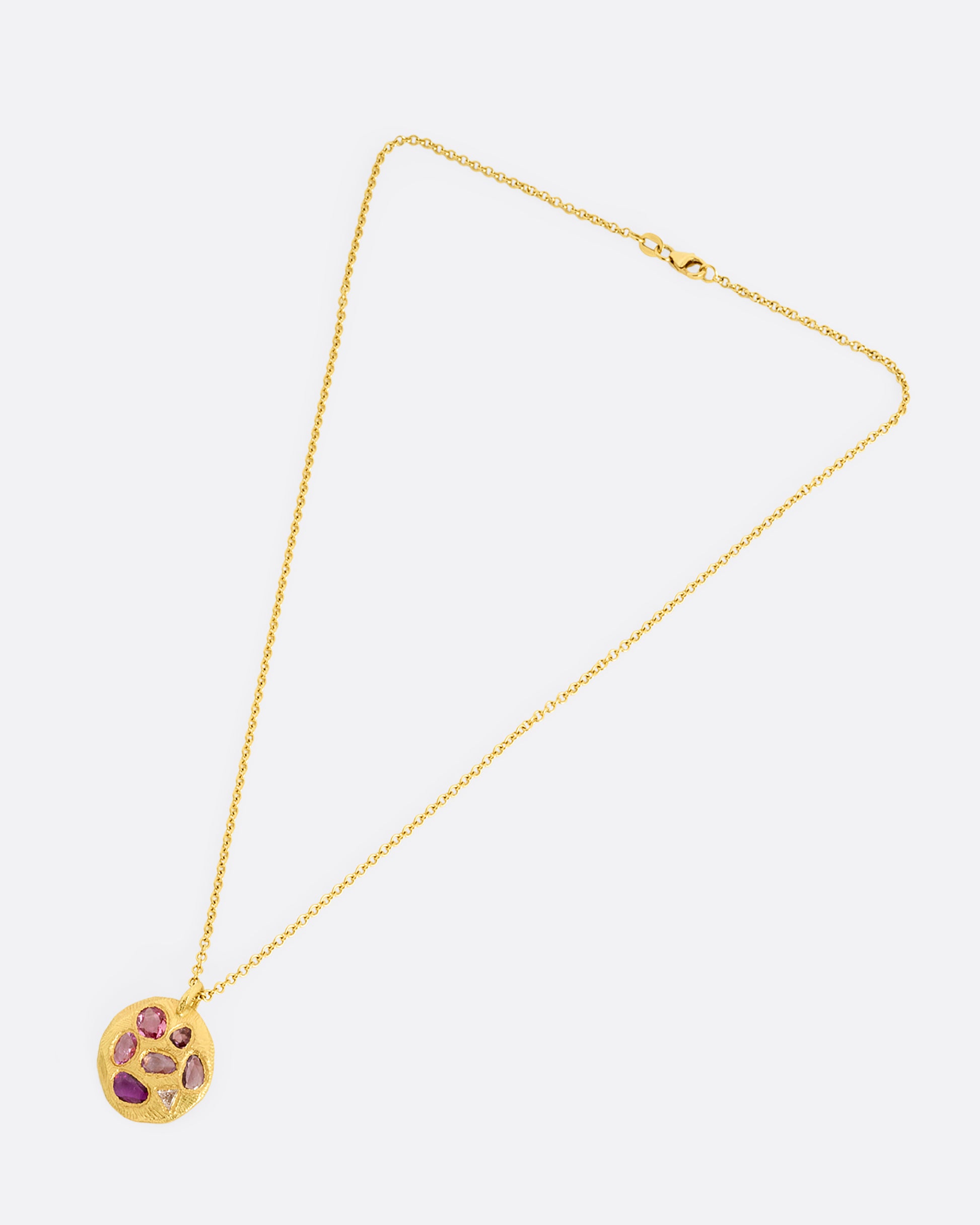 yellow gold necklace with pink sapphire pendant shown from afar