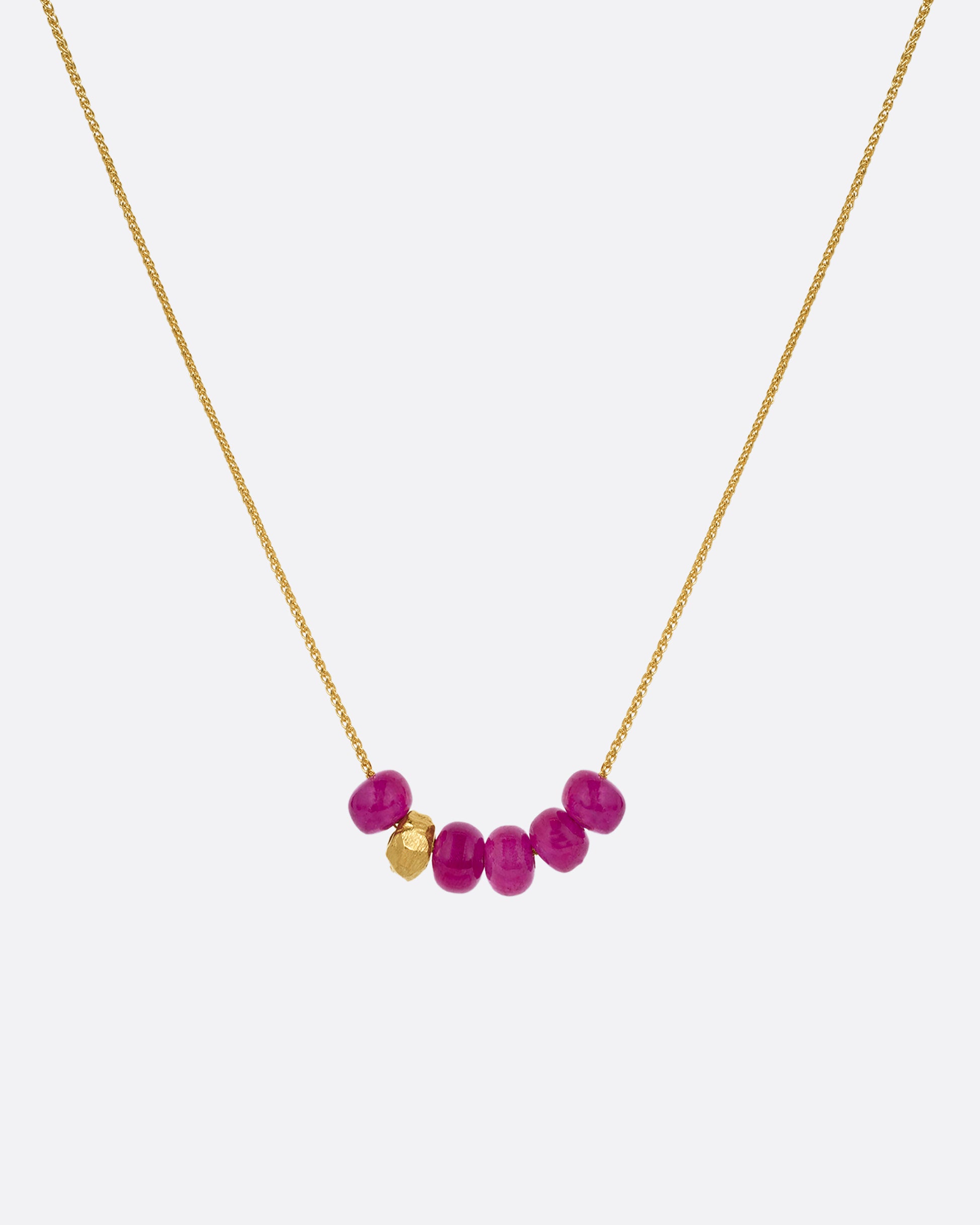 yellow gold necklace with pink sapphire pendant shown from afar