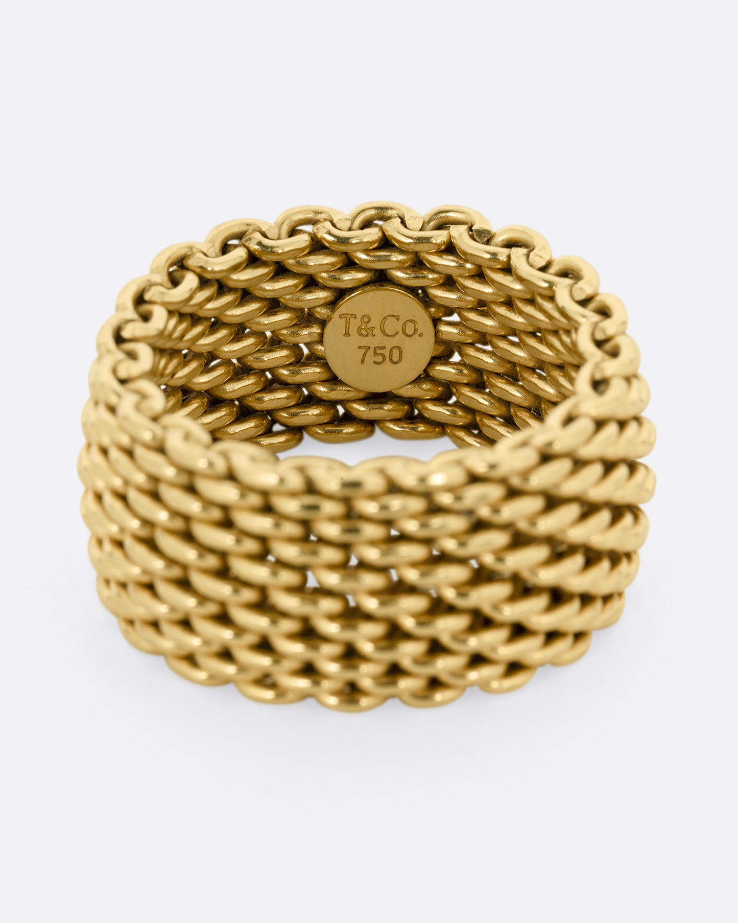 A yellow gold mesh Tiffany and Co. ring. Close up on the makers mark.