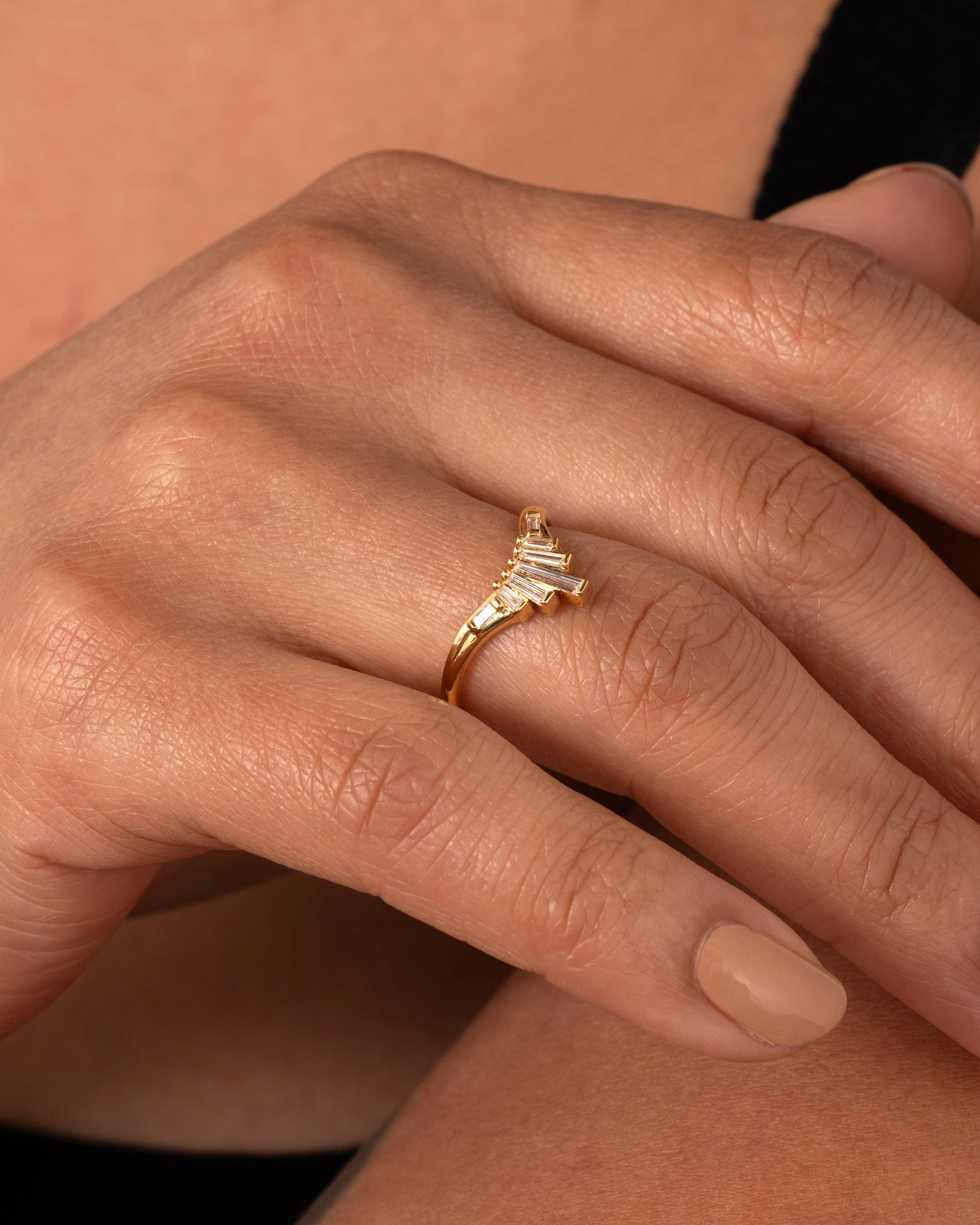 A yellow gold ring with graduated baguette diamonds. Shown worn on the finger