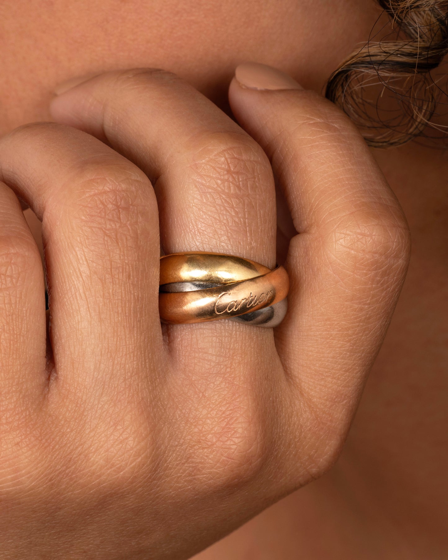 A yellow, rose and white gold wide rolling band from the heritage brand Cartier. Shown worn on a hand.