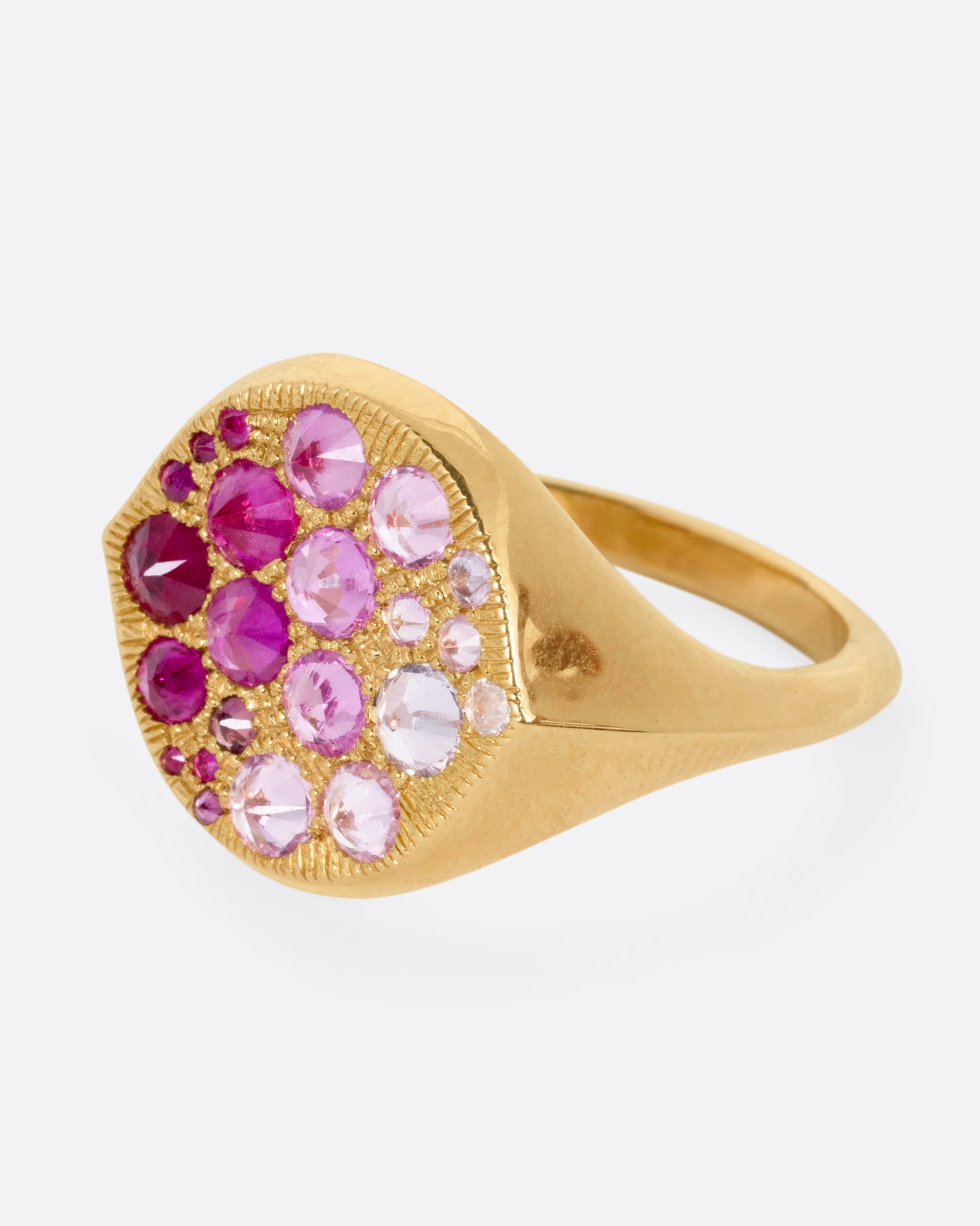 A yellow gold signet eye-shaped ring with an ombré of reverse set sapphires and rubies. Shown from the side.