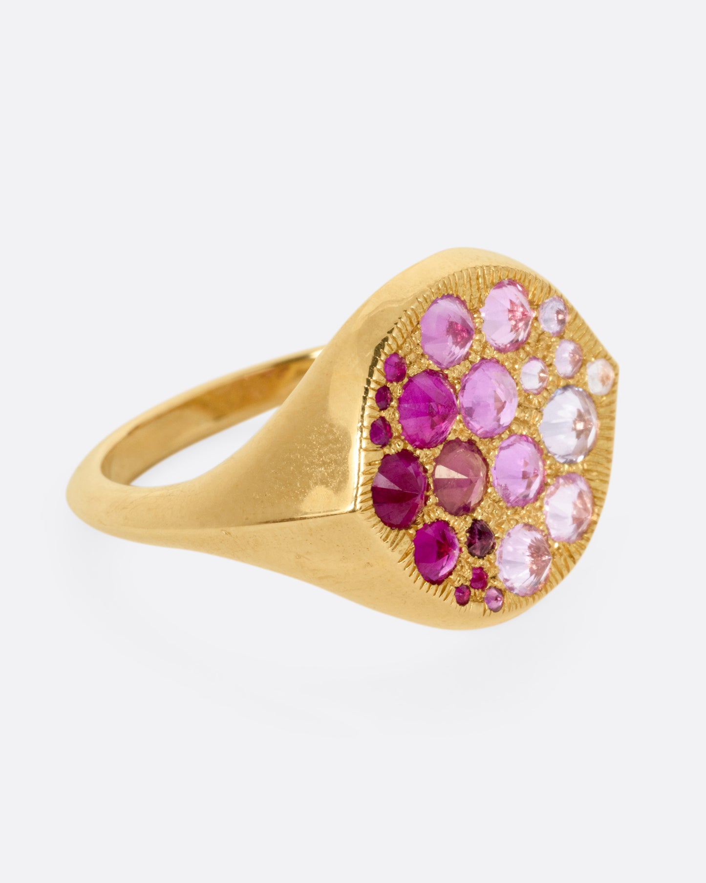 A yellow gold signet eye-shaped ring with an ombré of reverse set sapphires and rubies. Shown from the side.
