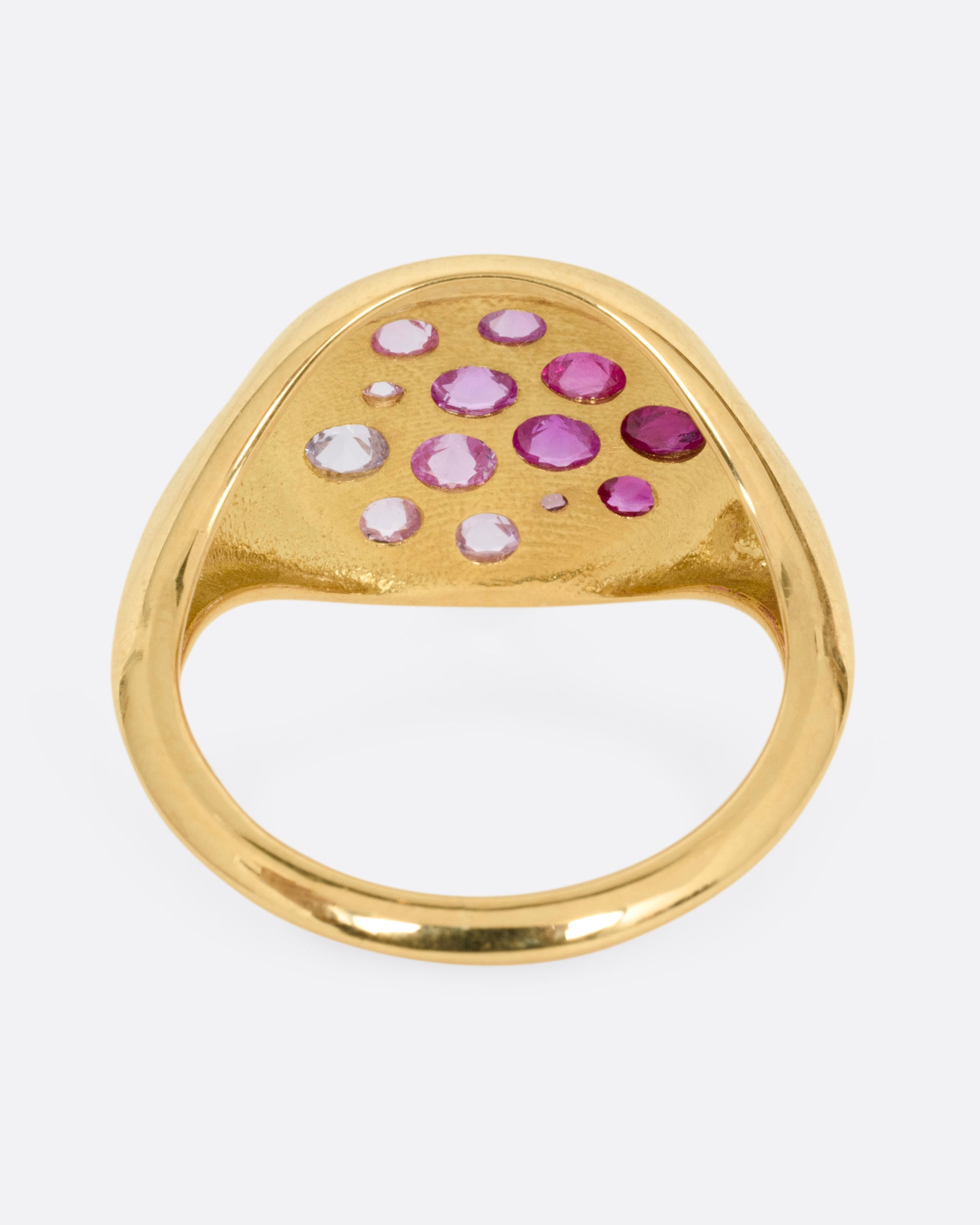 A yellow gold signet eye-shaped ring with an ombré of reverse set sapphires and rubies. Shown from the back.