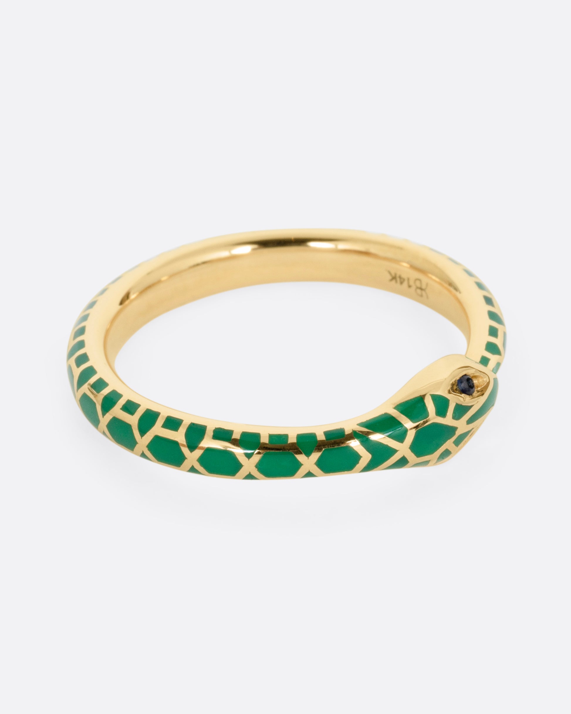 A yellow gold  ouroboros ring with sapphire eyes and a green enamel snake skin pattern, shown from the side.