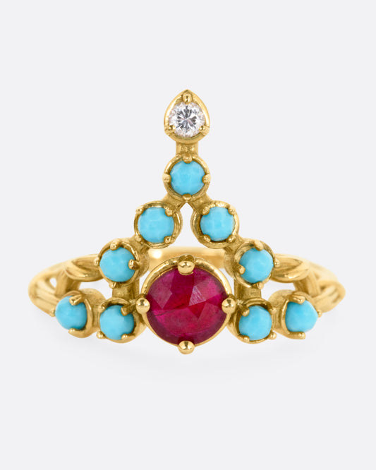 A yellow gold stacker ring with a ruby center surrounded by turquoise cabochons with a diamond tip, shown from the front.