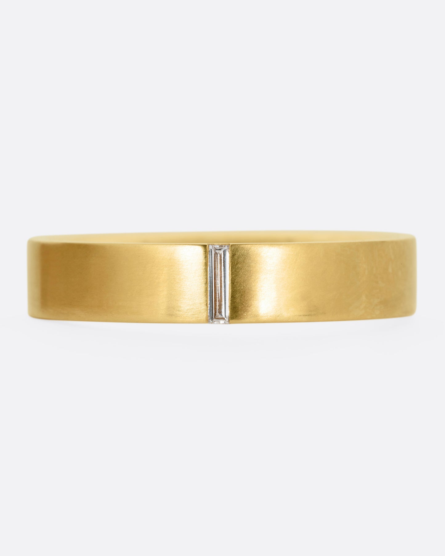 A yellow gold ring with a baguette diamond, shown from the front.