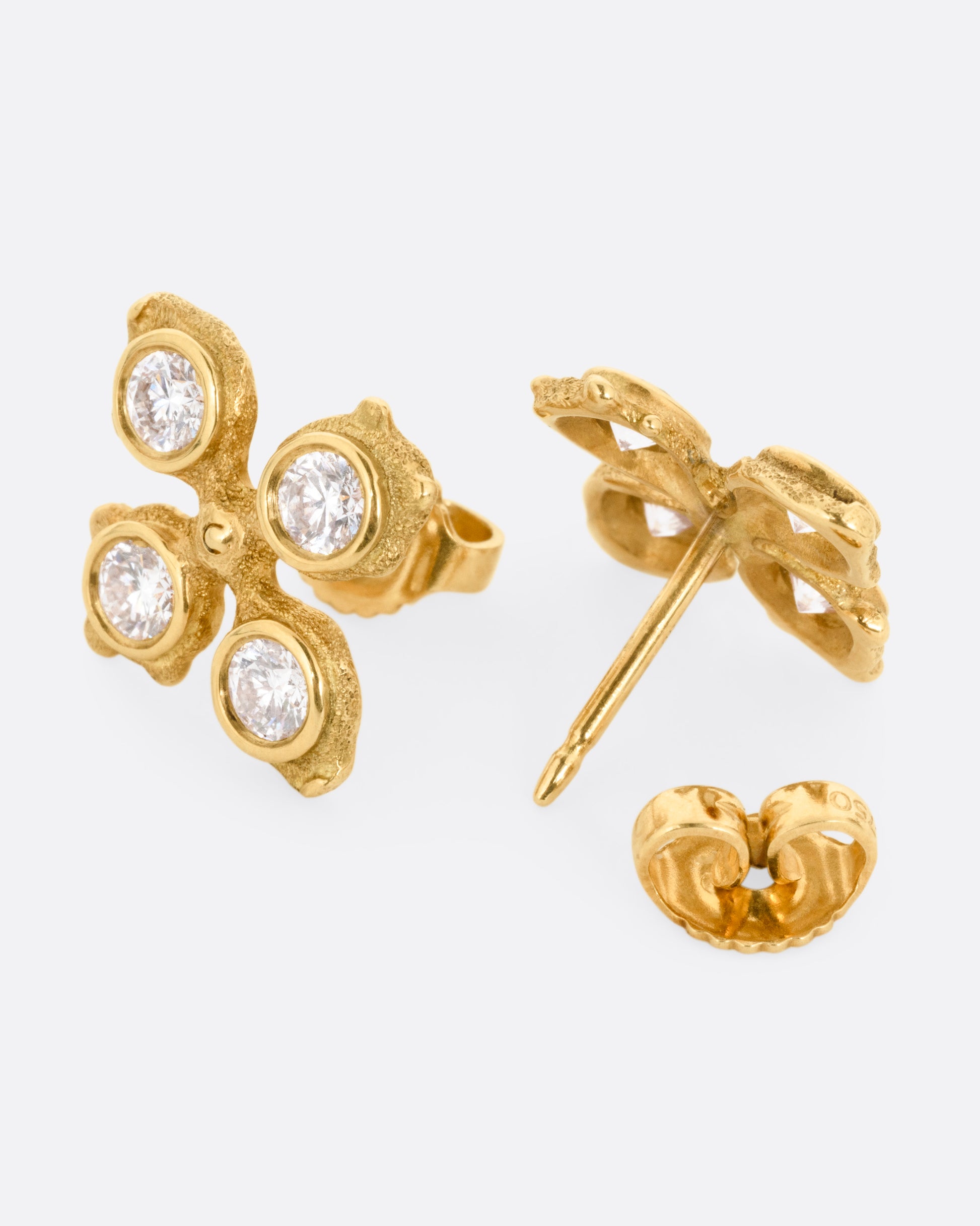 A pair of yellow gold club shaped stud earrings with four white diamonds in each. One earring is shown from the front, the other from the back open.