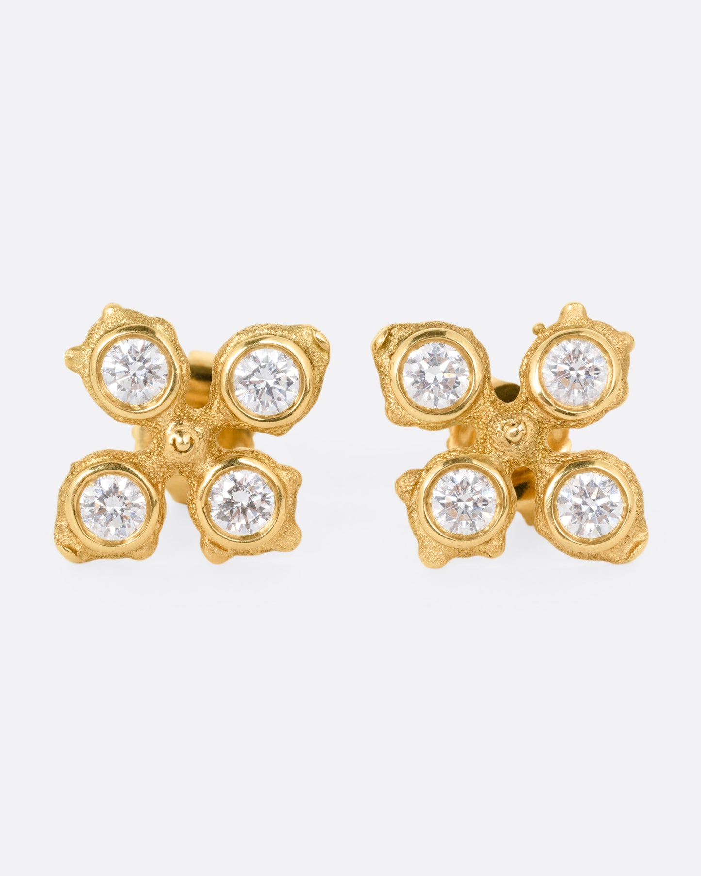 A pair of yellow gold club shaped stud earrings with four white diamonds in each. Shown from the front.