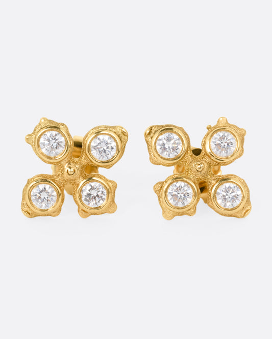 A pair of yellow gold club shaped stud earrings with four white diamonds in each. Shown from the front.