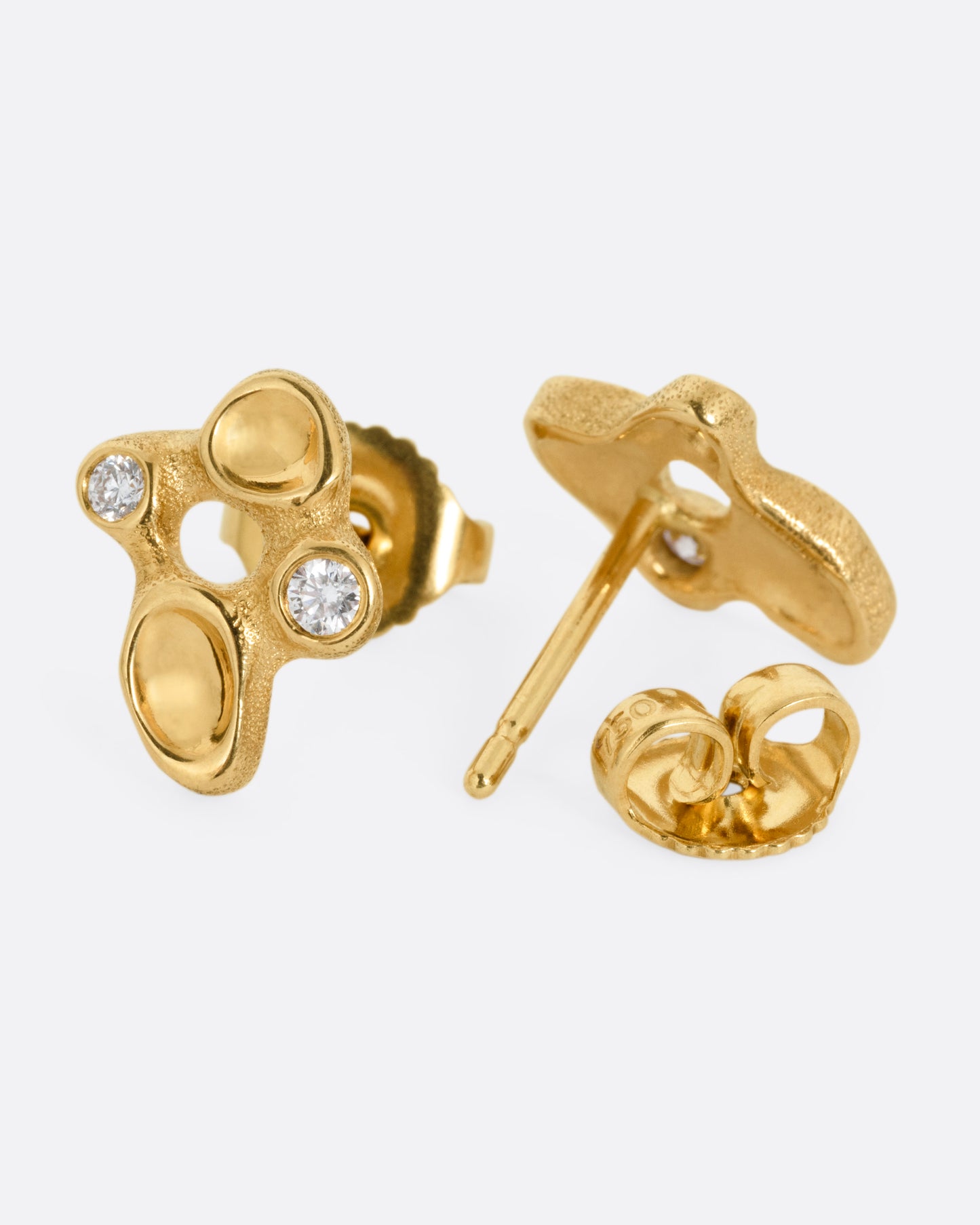 A pair of yellow gold cluster stud earrings with diamonds and smooth depressions. One earring is shown from the front, the other is shown from the back open.