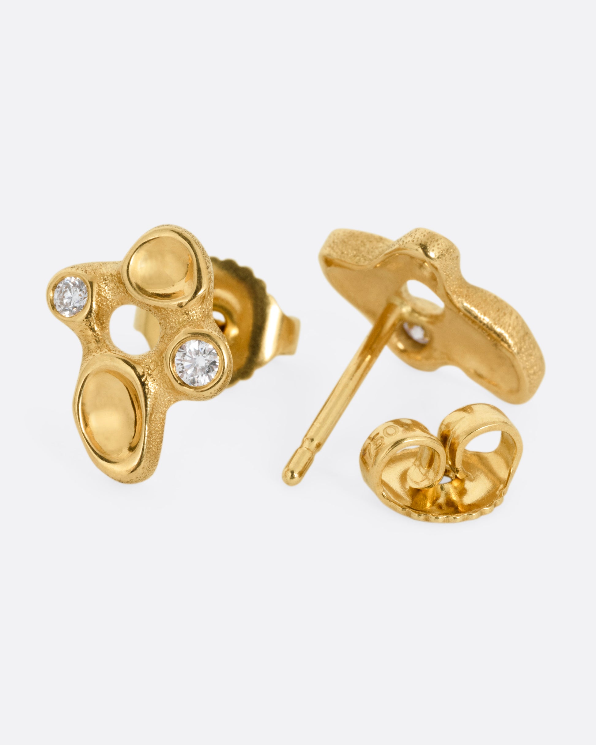 A pair of yellow gold cluster stud earrings with diamonds and smooth depressions. One earring is shown from the front, the other is shown from the back open.