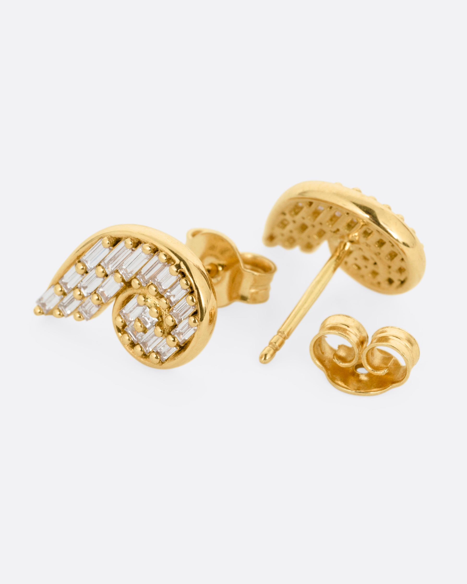 A pair of yellow gold curling earrings filled with baguette diamonds. One earring is shown from the front, the other from the back open.
