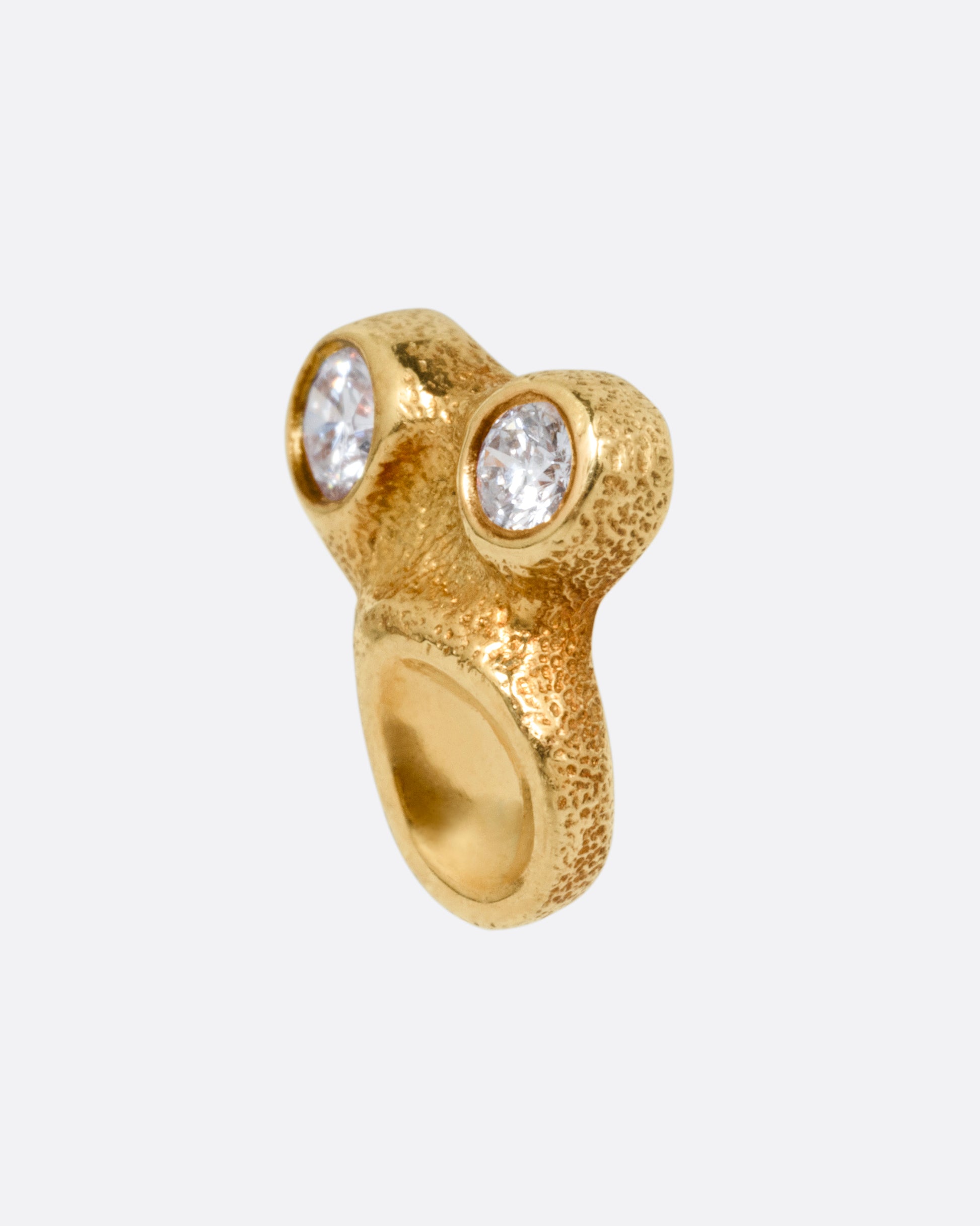 A yellow gold stud earring with two bezel set diamonds and smooth depressions, shown from the side.