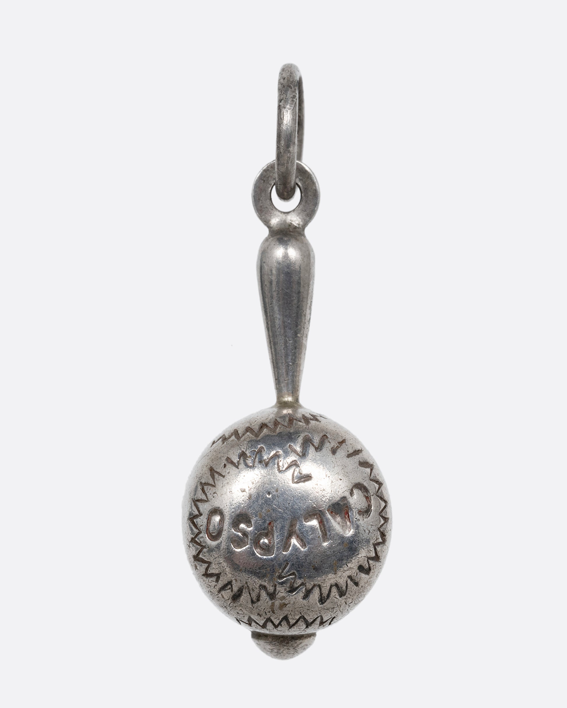 A silver maraca charm with 'Calypso' engraved on it. Shown from the front.