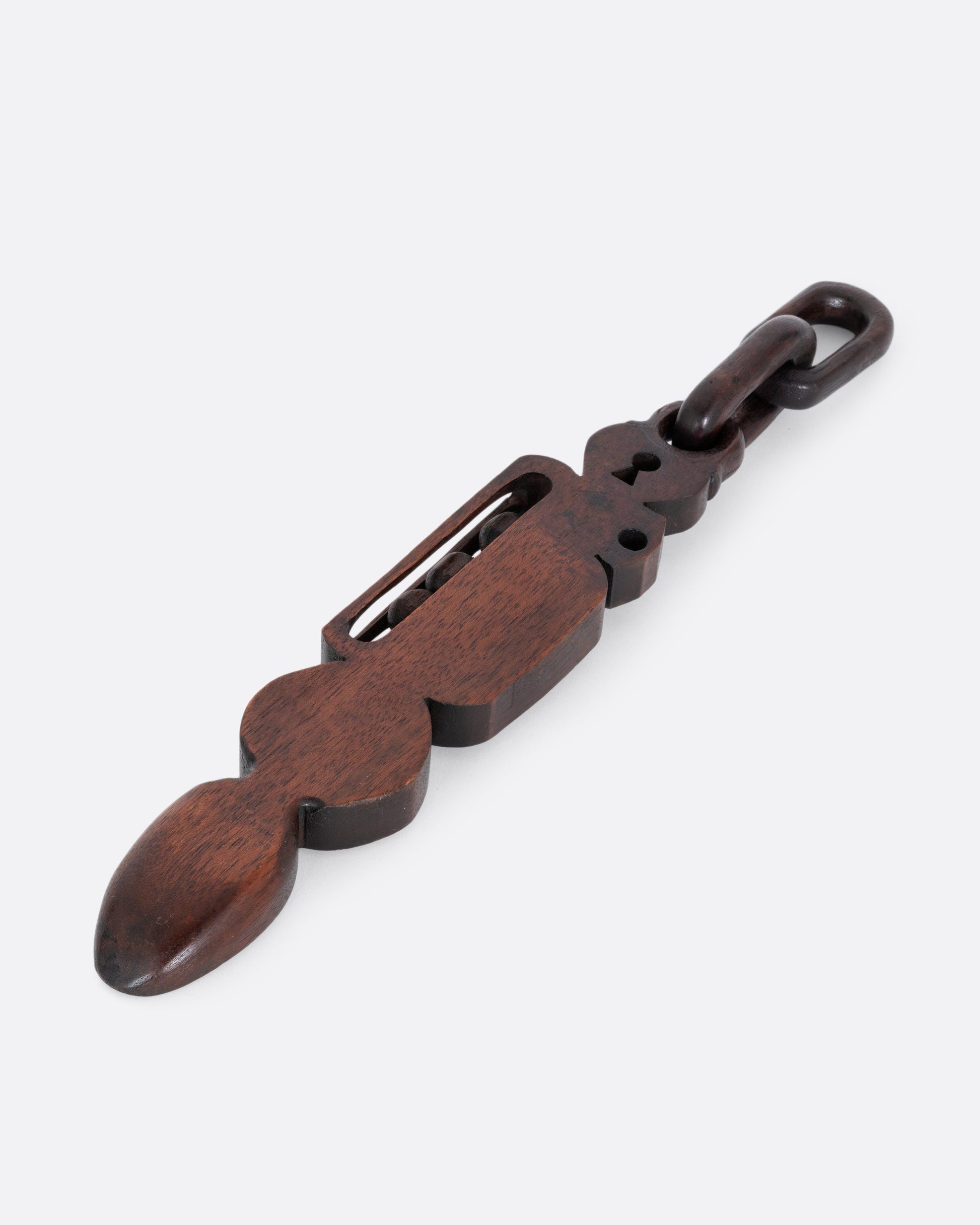 A wooden whimsy spoon hand carved from a single piece of wood. A padlocked heart with chain links, a shield, gryphon emblem, and three moving balls are all carved on its handle. Shown from the back.