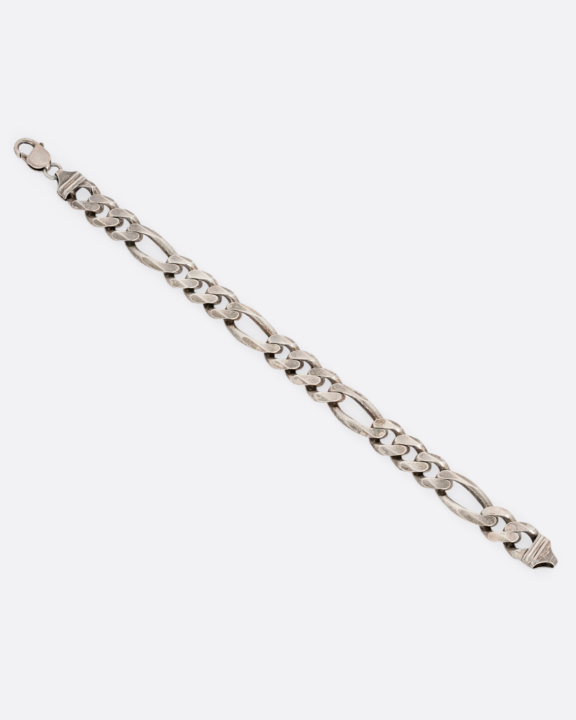 A wide silver figaro chain bracelet. Shown open from the top.