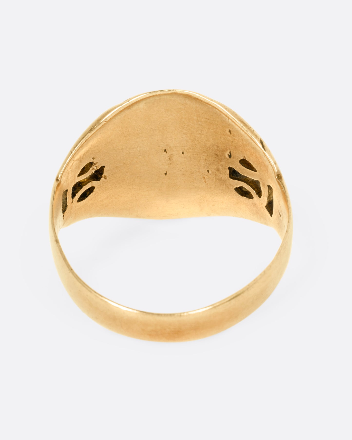 A yellow gold ring with an oval face and an ornate band, shown from the back.