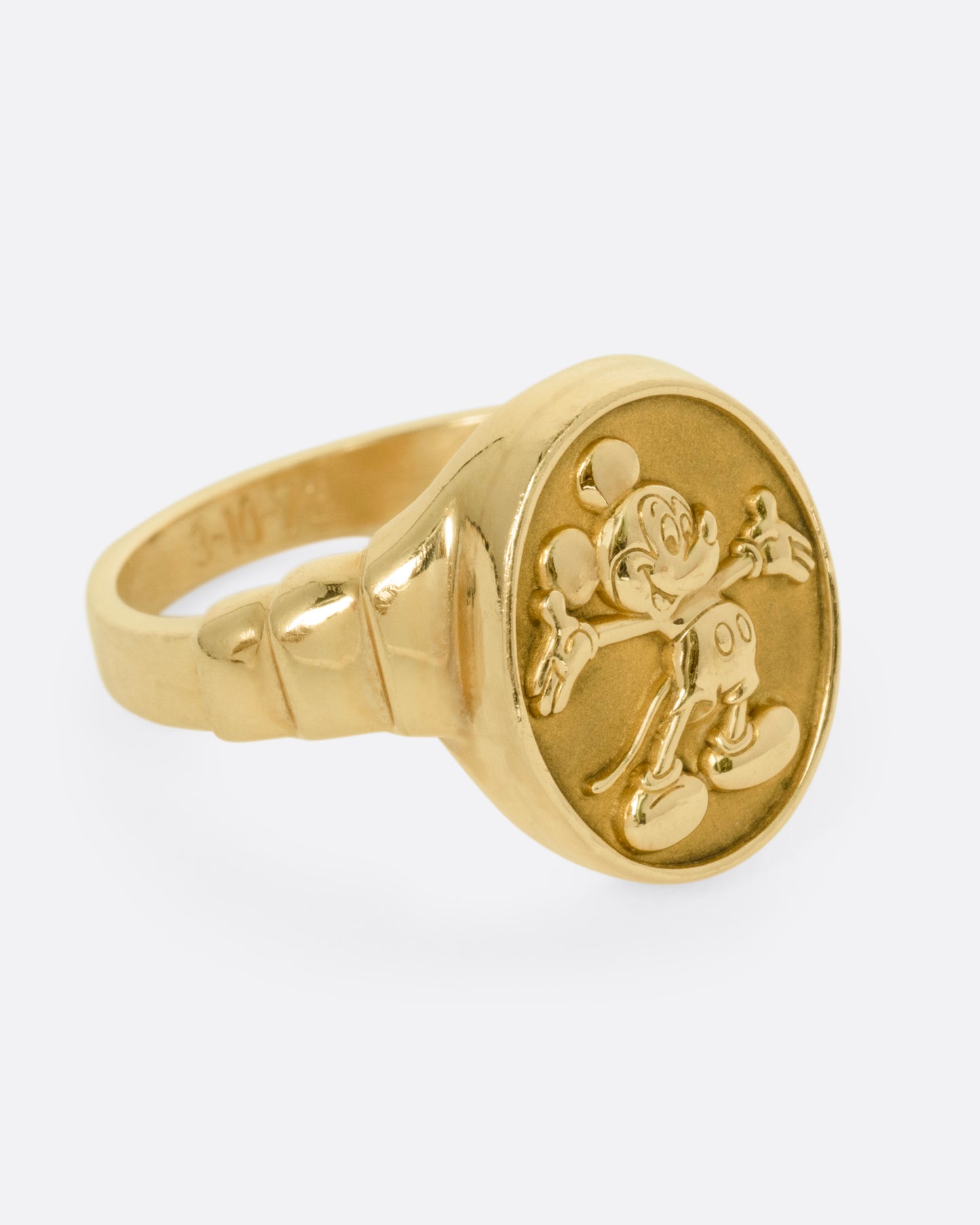 A yellow gold ring with Mickey Mouse on its face and '1973' on its shoulder, shown from the side.