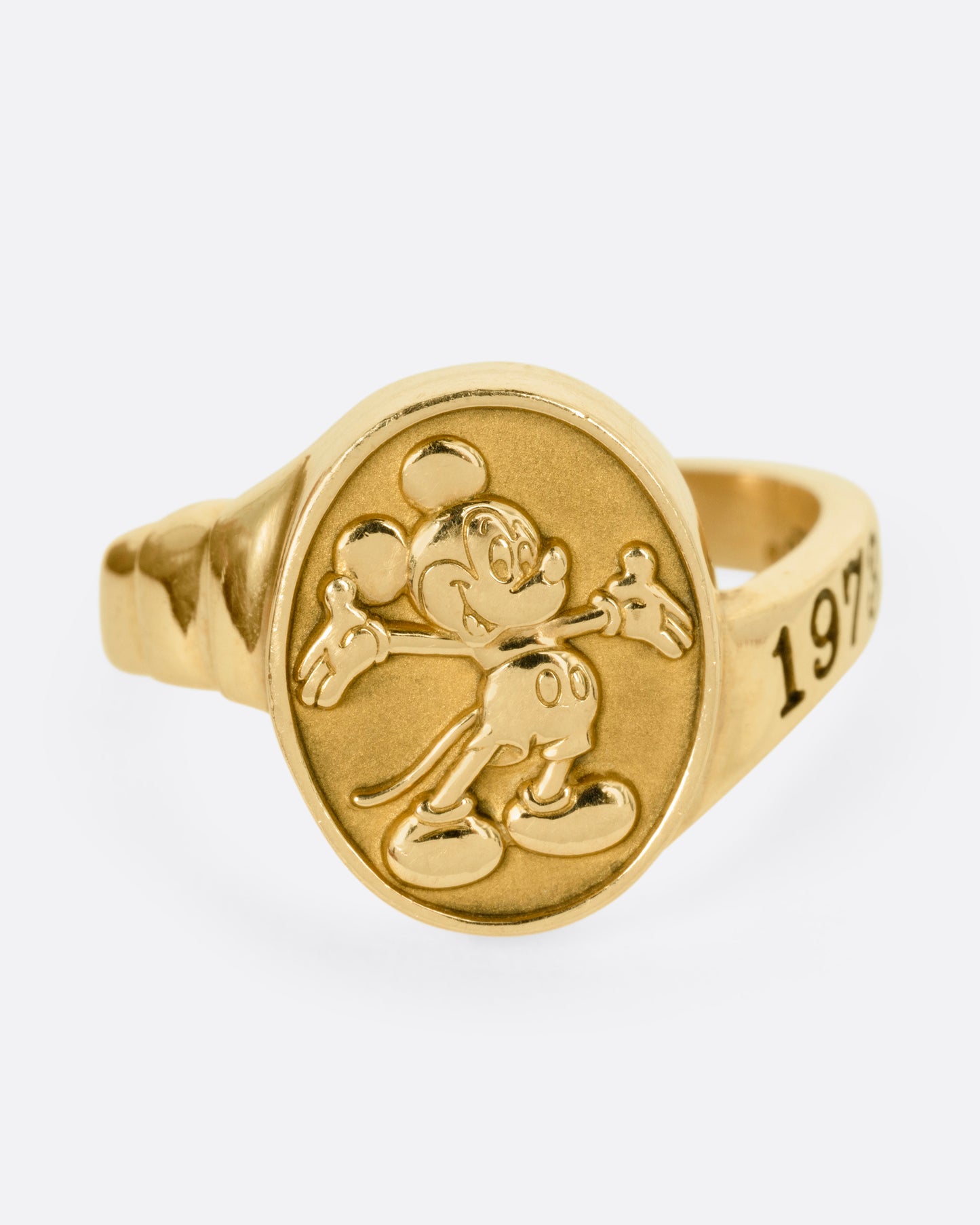 A yellow gold ring with Mickey Mouse on its face and '1973' on its shoulder, shown from the front.