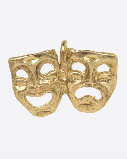 A yellow gold theatrical mask charm, with one smiling, and one frowning. Show from the front.