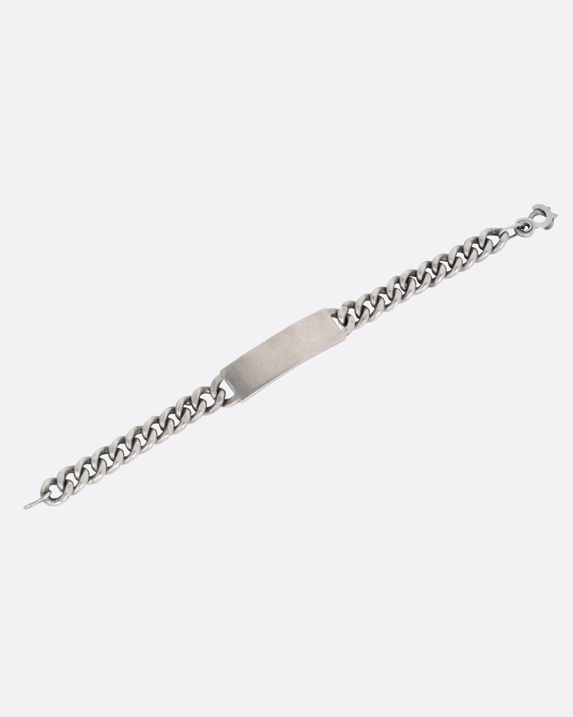 A silver curb chain ID bracelet, shown open from the front.