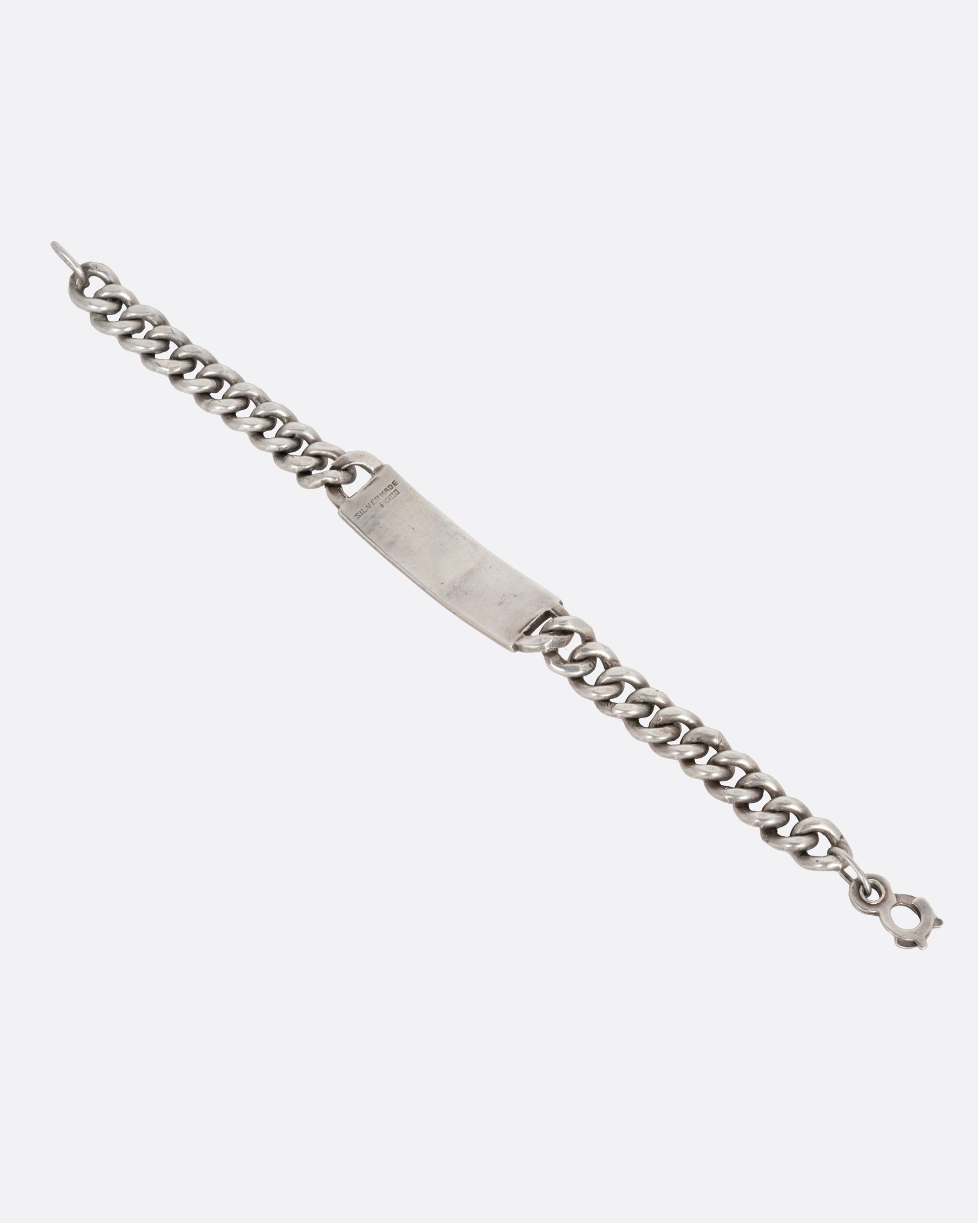 A silver curb chain ID bracelet, shown open from the back.