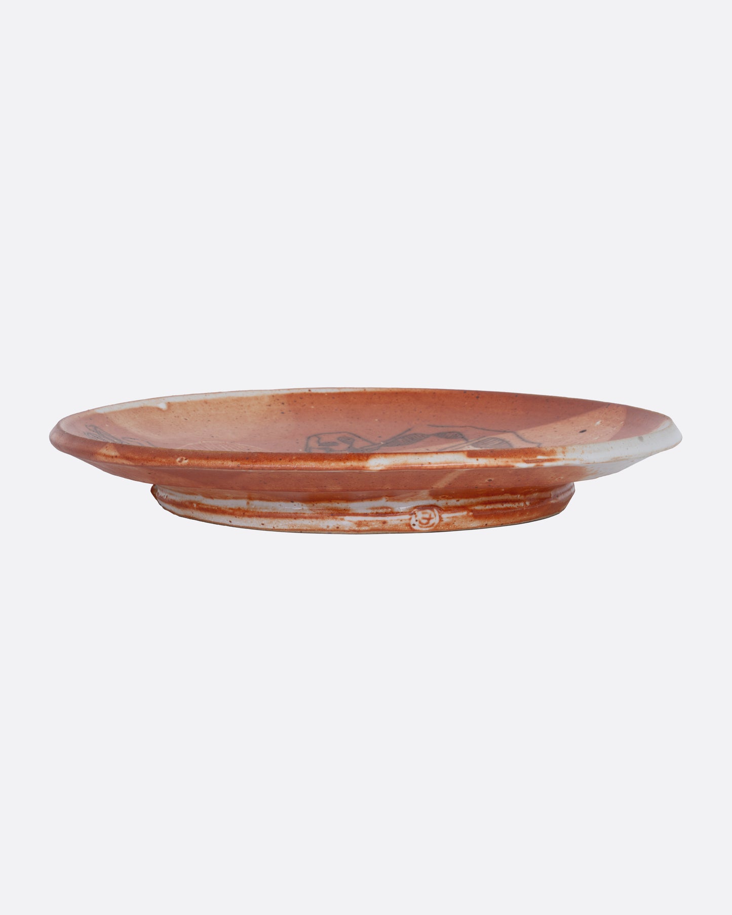 A ceramic plate with a reddish-brown glaze, shown from the side.