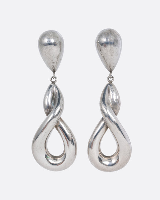 A pair of silver drop earrings with a twisted silhouette. Shown from the front.