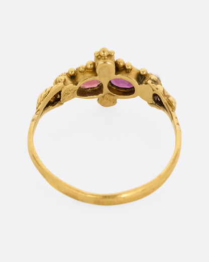 A yellow gold ring with garnets and seed pearls. Shown from the back.
