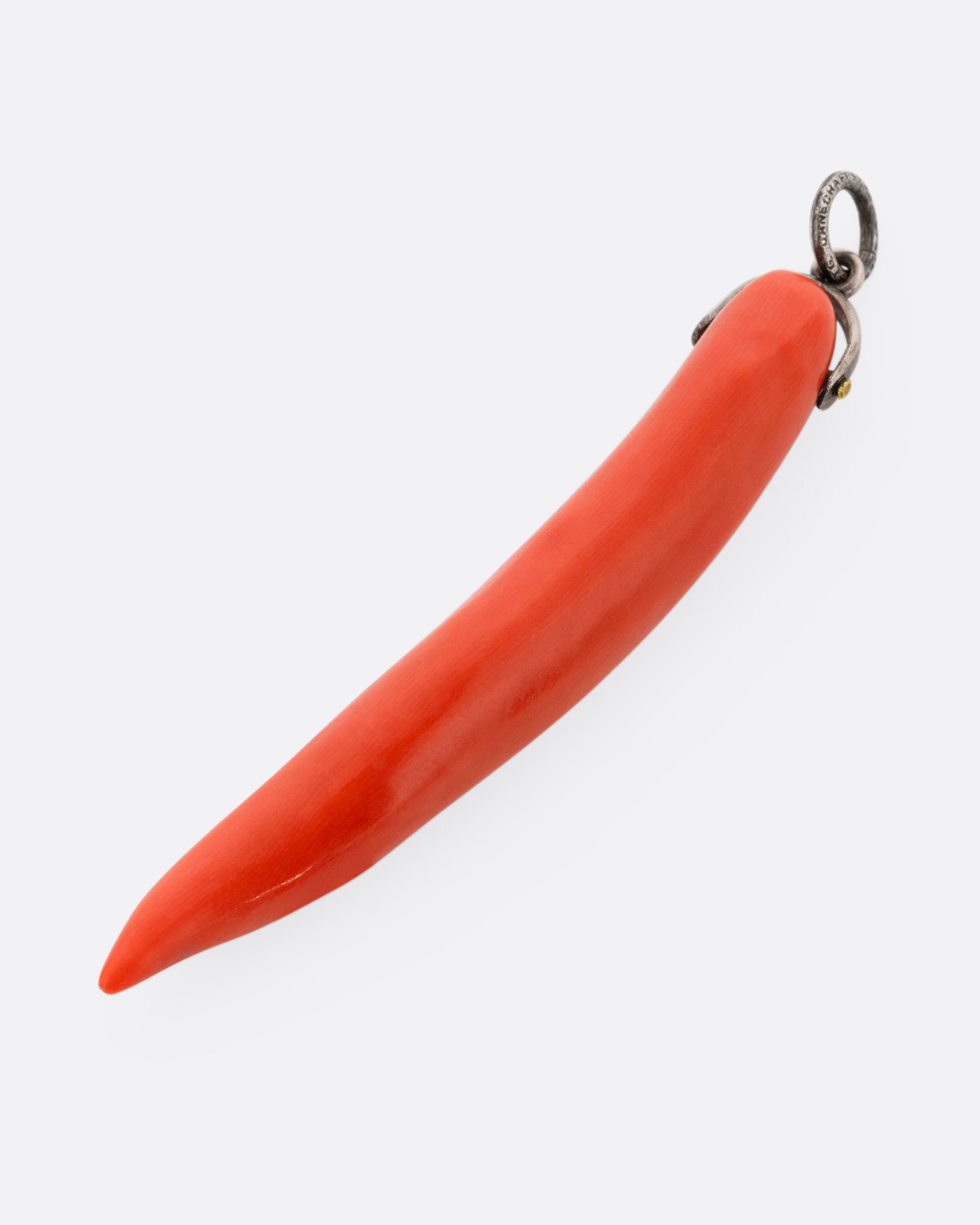 A coral branch charm on a silver bail. Shown lying flat diagonally from the front.