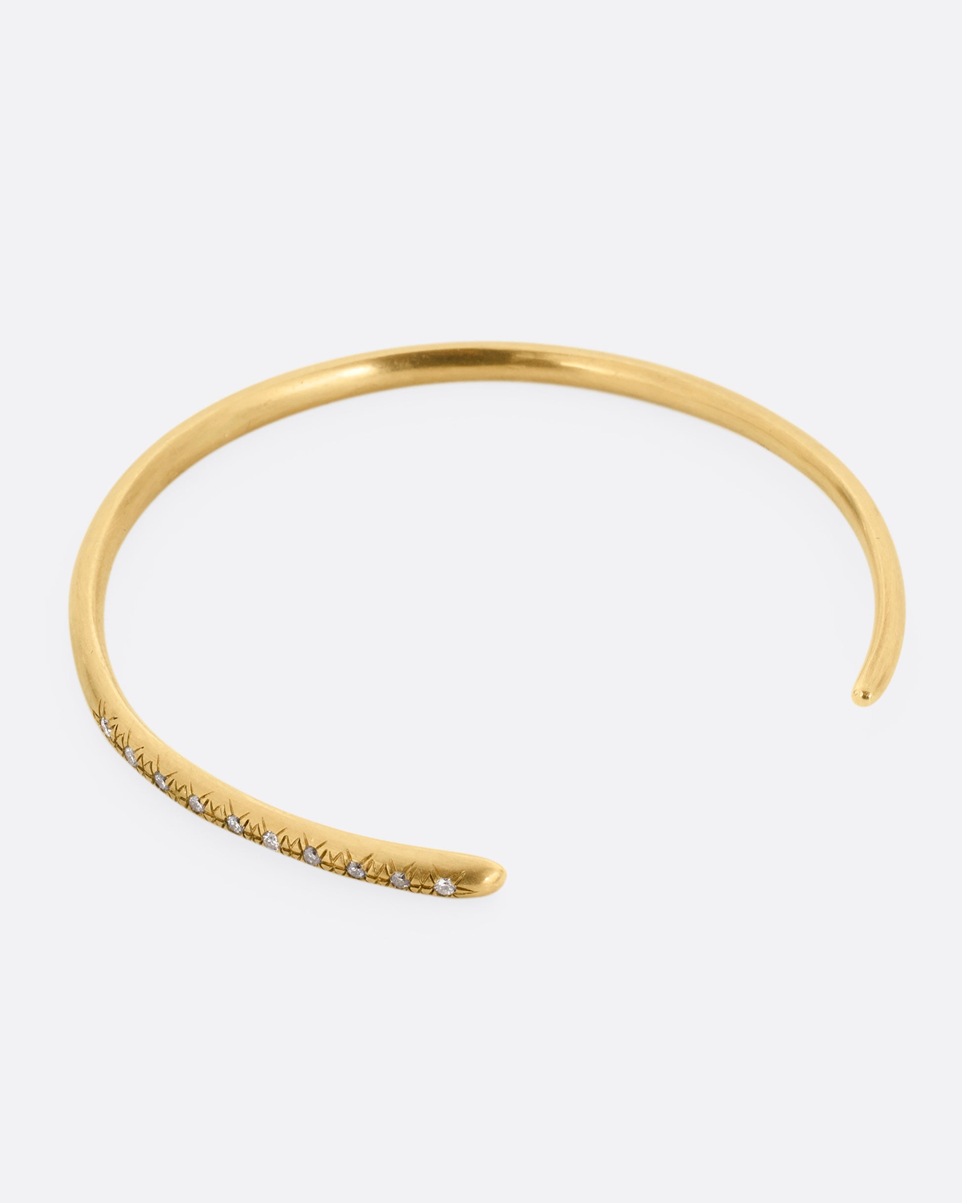 A yellow gold open cuff bracelet with diamonds. Shown from above.