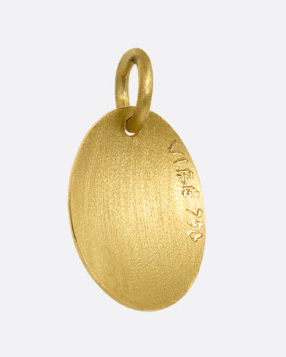 A yellow gold medallion with a diamond eyed bug with green enamel striped wings. Shown from the back.