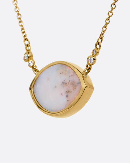 A yellow gold cable chain necklace with a large eye shaped opal pendant and diamond accents. Shown from the side.