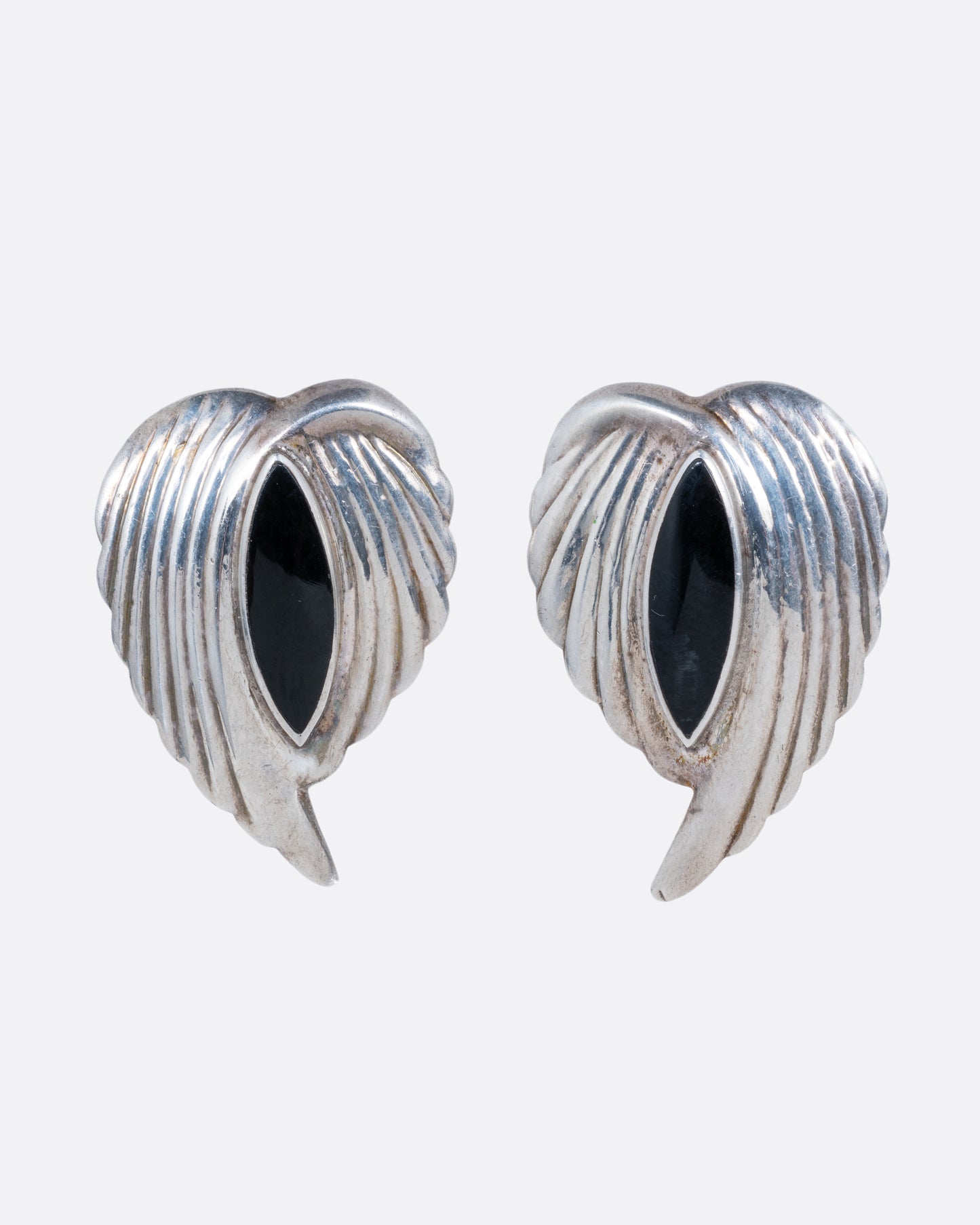 A pair of silver leaf stud earrings with bezel set marquis onyxes at the center. Shown from the front.