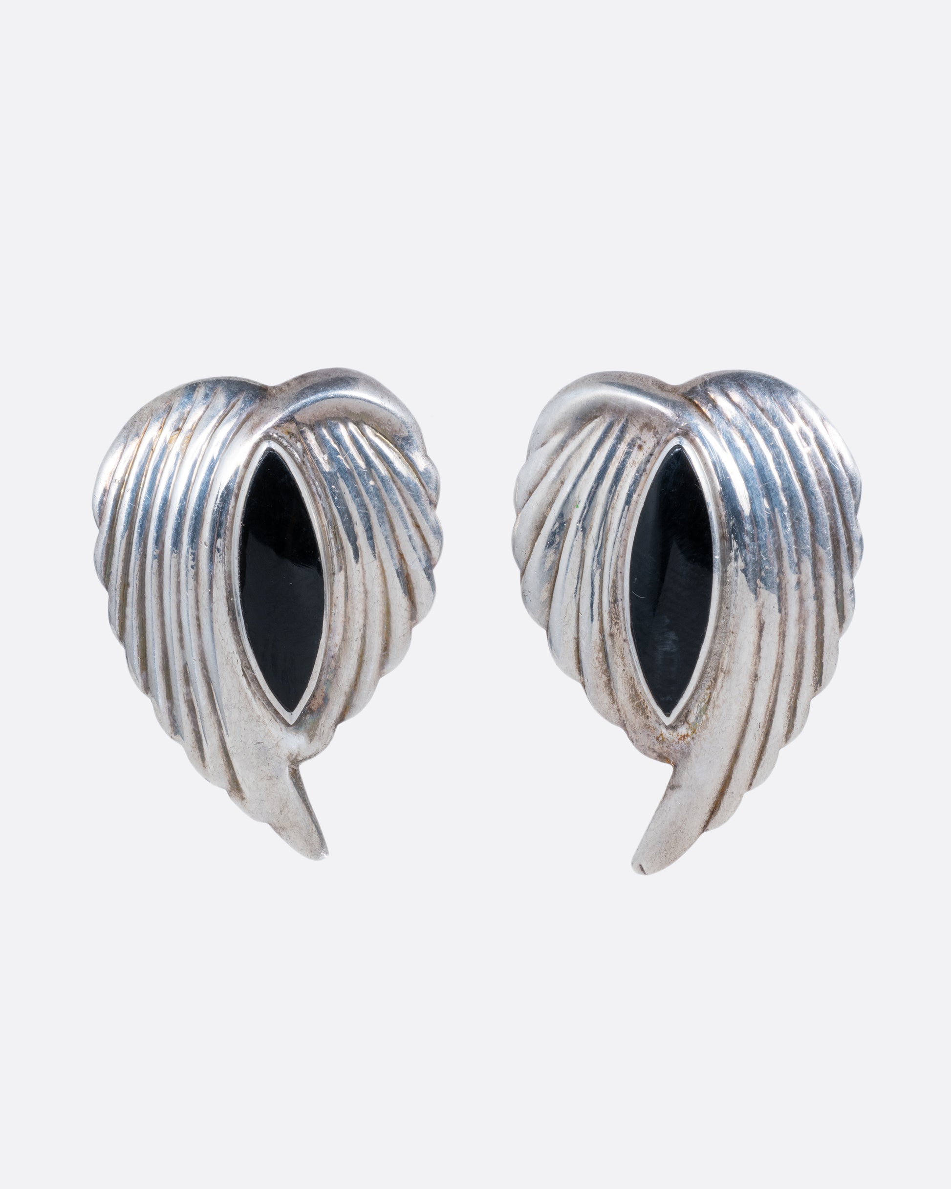 A pair of silver leaf stud earrings with bezel set marquis onyxes at the center. Shown from the front.